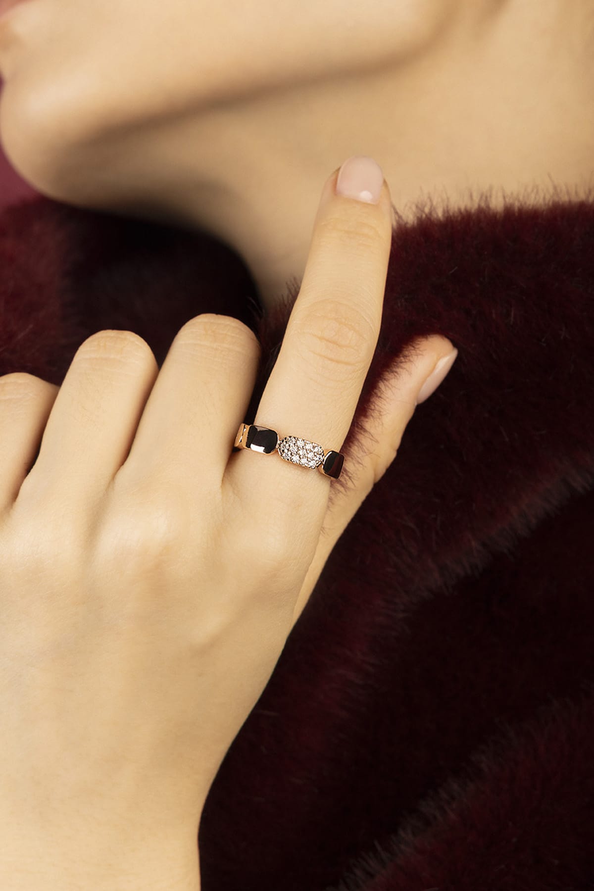 Woman wearing APM Monaco ring, a whisper of noir elegance against burgundy softness.