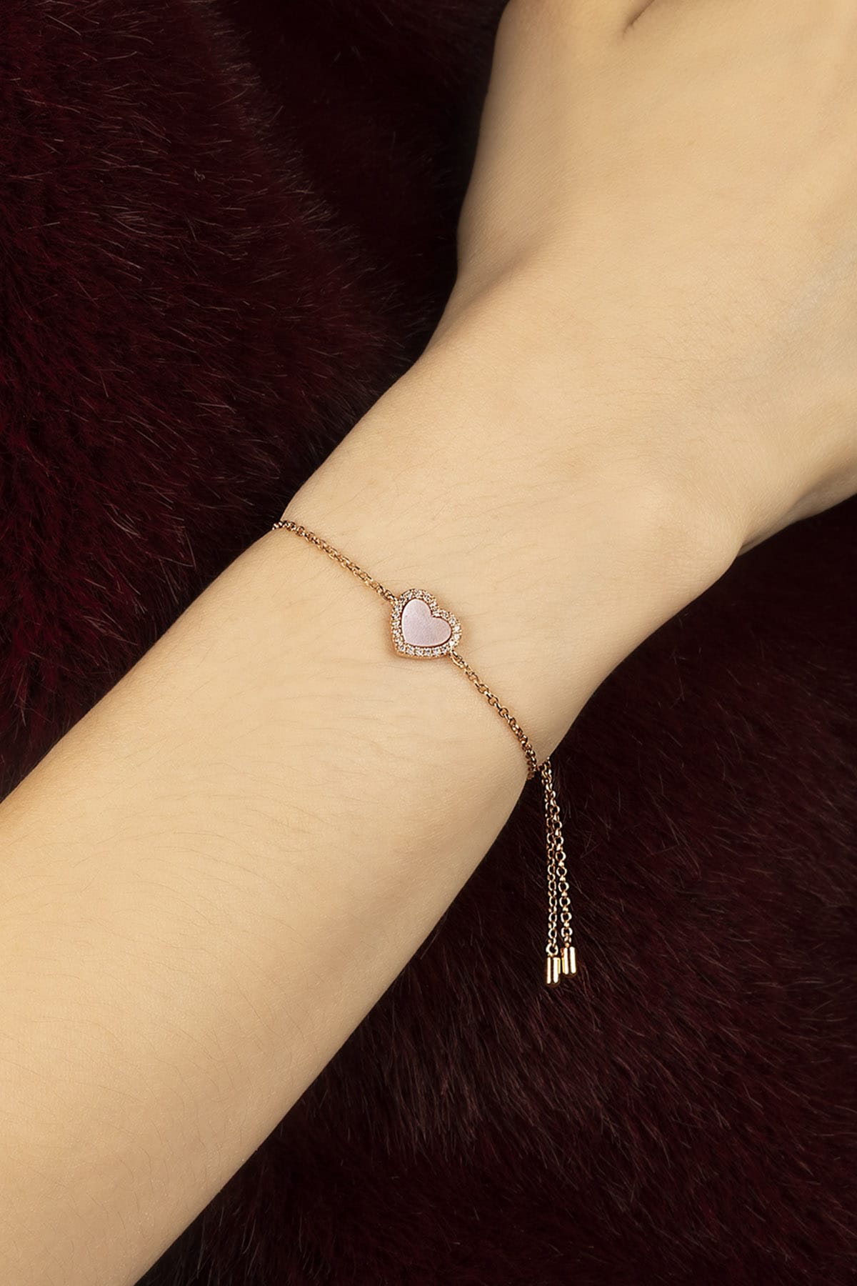 Woman wearing APM heart bracelet, a soft romance whispered in rose.