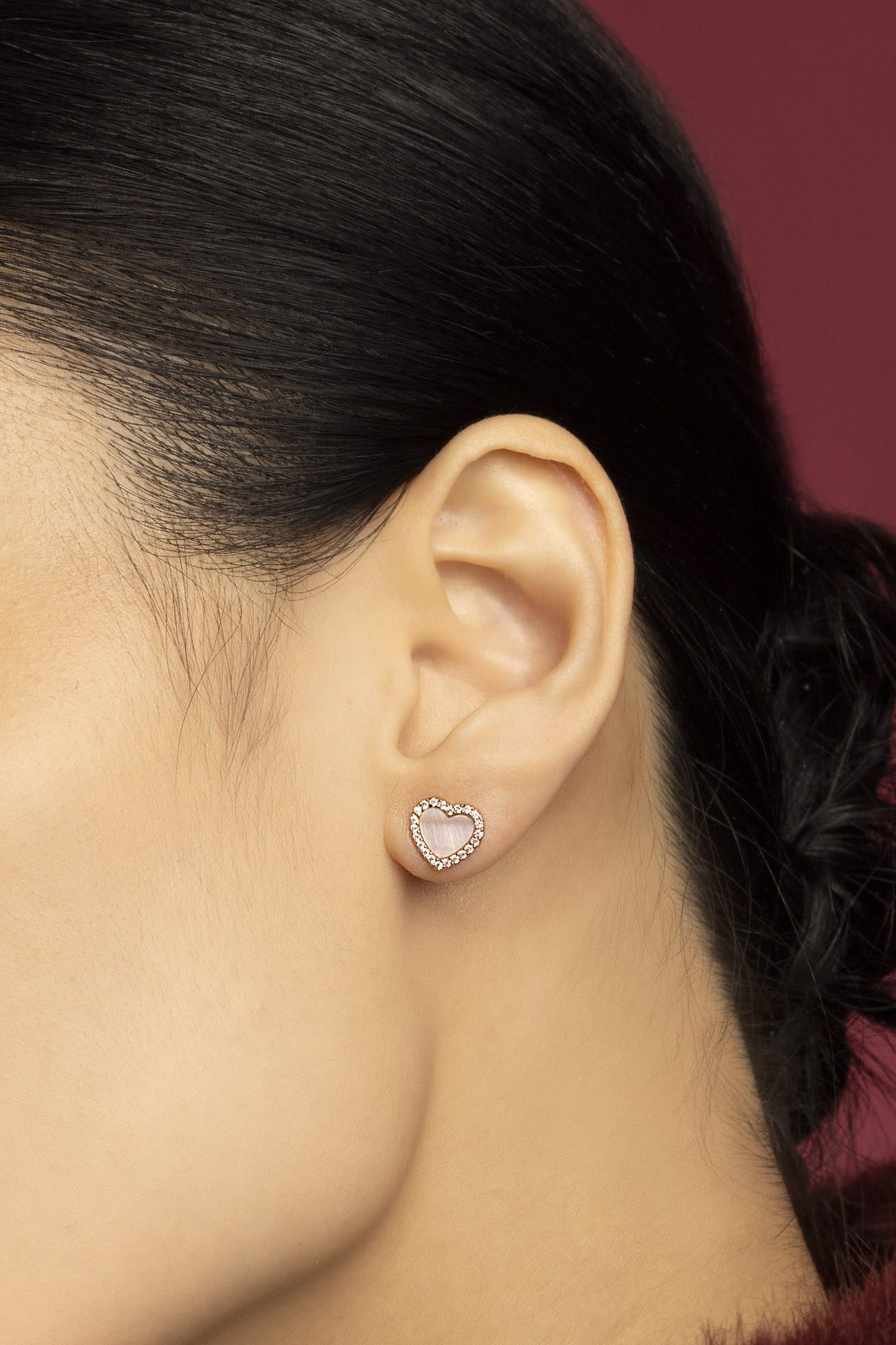 Woman wearing APM heart stud earrings, a tender glow of romance.