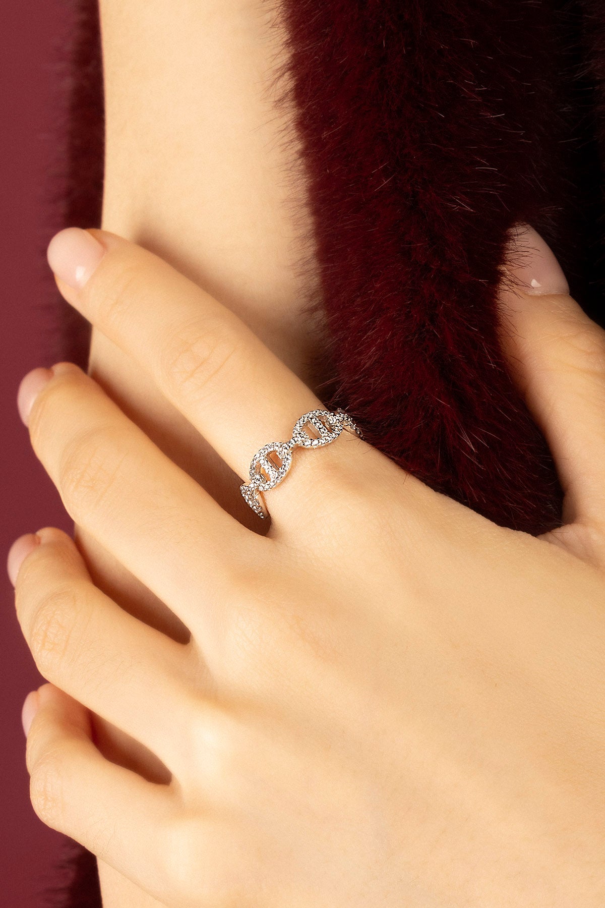 Woman wearing APM Morse Ring, a delicate shimmer against soft burgundy elegance.