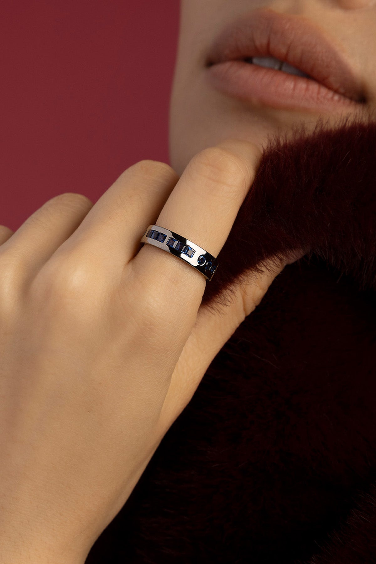 Woman wearing APM ring, midnight blue stones in rhodium finish, quiet sophistication.