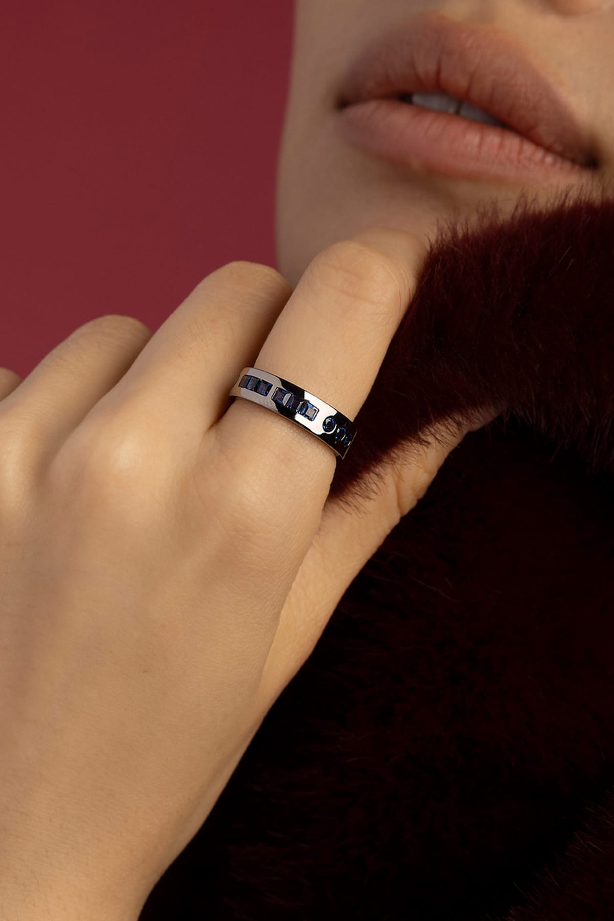 Woman wearing APM ring, midnight blue stones in rhodium finish, quiet sophistication.