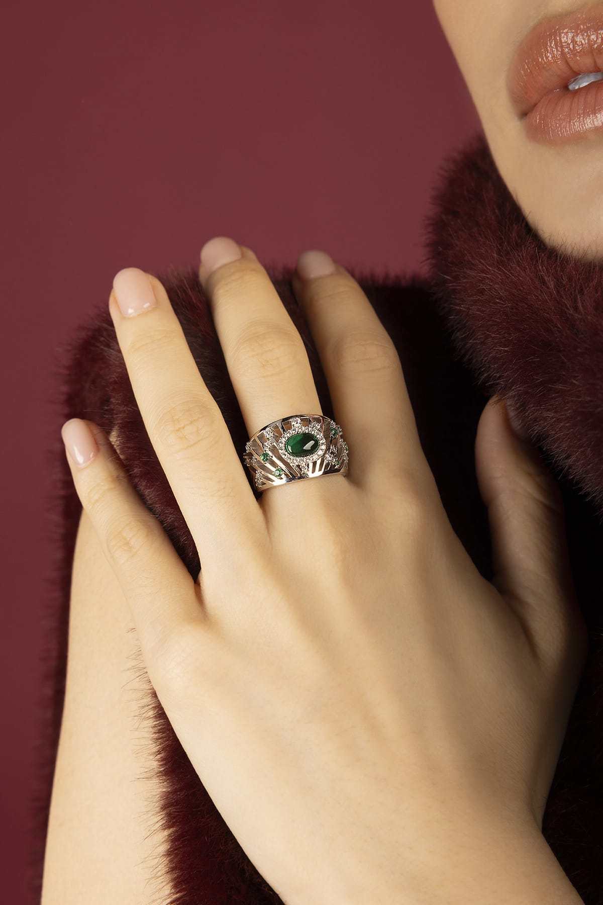 Woman wearing APM Monaco ring, emerald allure with a rhodium finish glow.