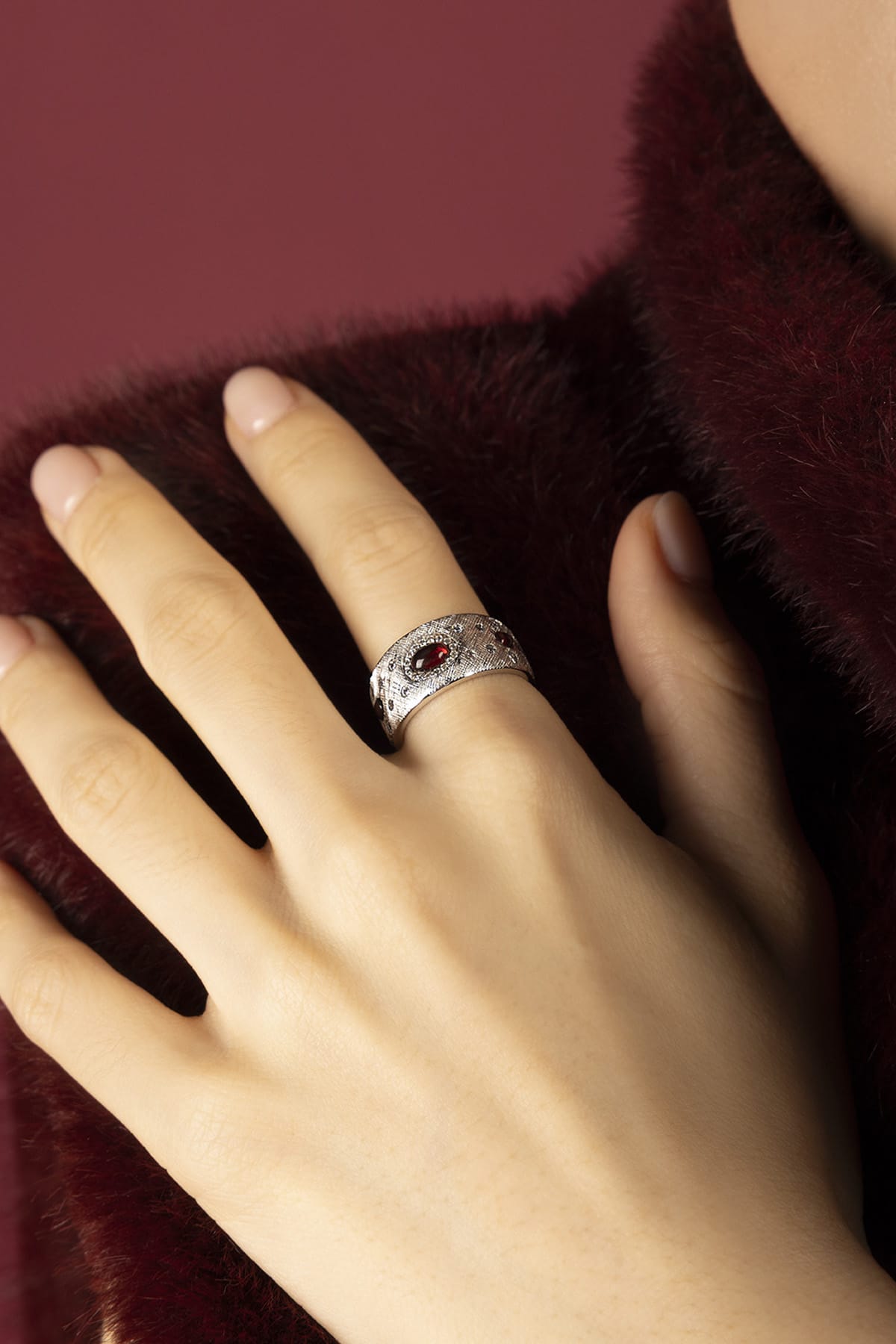 Woman wearing APM Monaco ring, a bold whisper of crimson elegance.