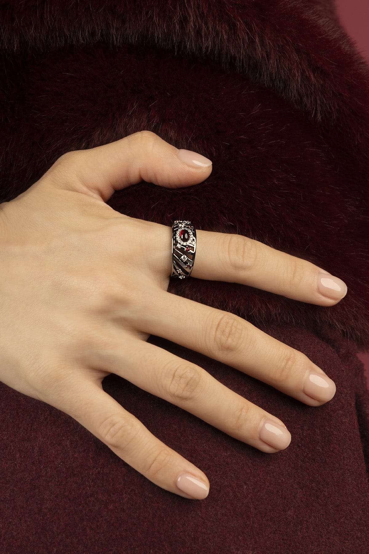 Woman wearing APM Morse Ring, a quiet spark against burgundy softness.