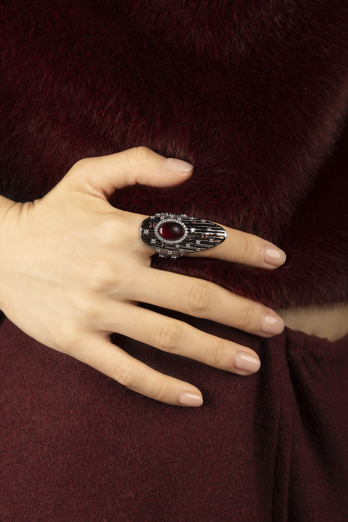 Woman wearing APM Ring, a bold red gem framed in rhodium finish elegance.