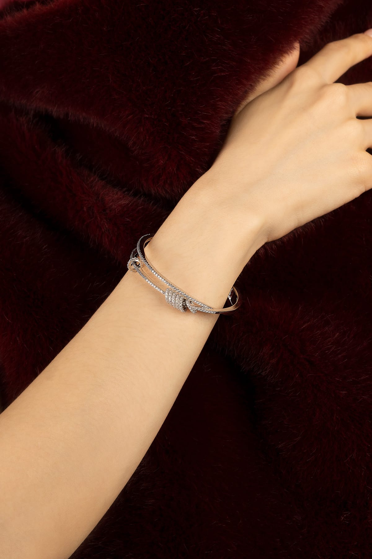 Woman wearing APM bangle, a whisper of rhodium finish against velvet warmth.