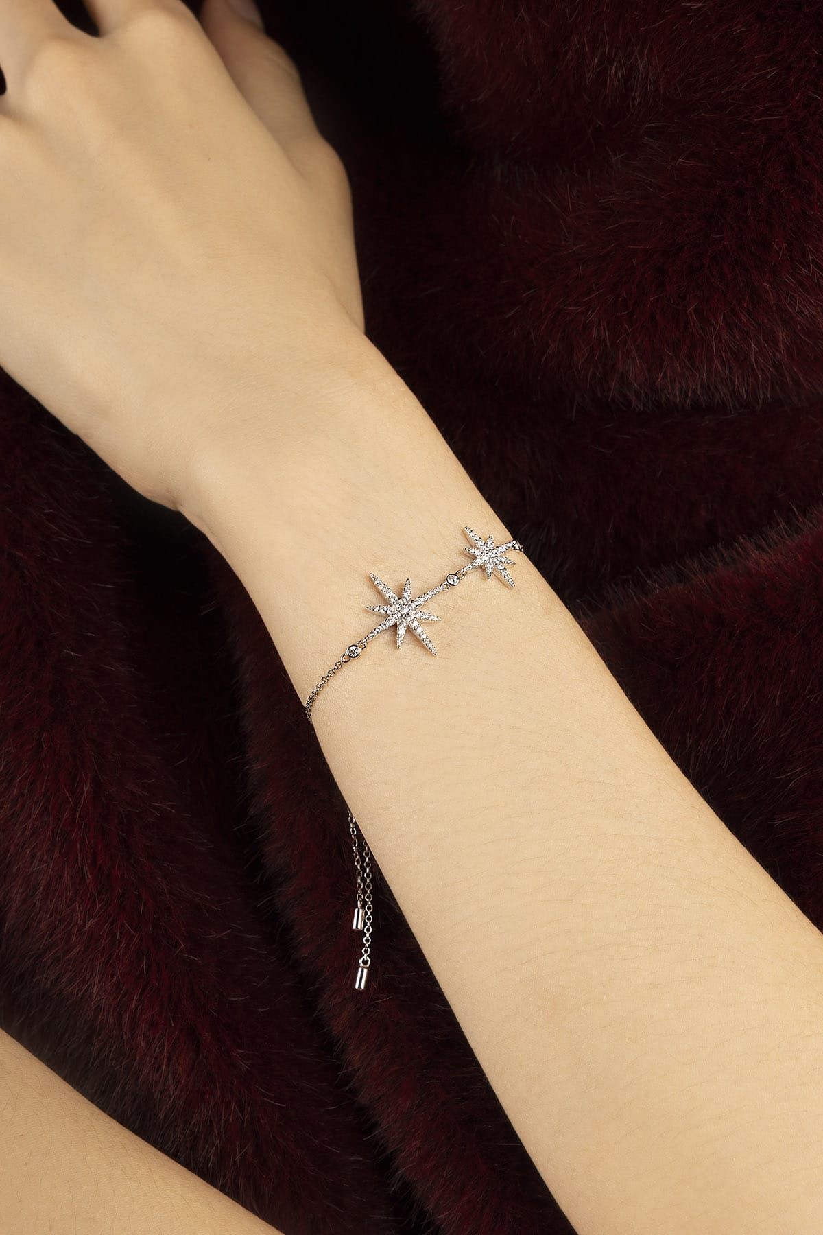 Woman wearing APM Météorites Bracelet, a celestial glow against velvet warmth.