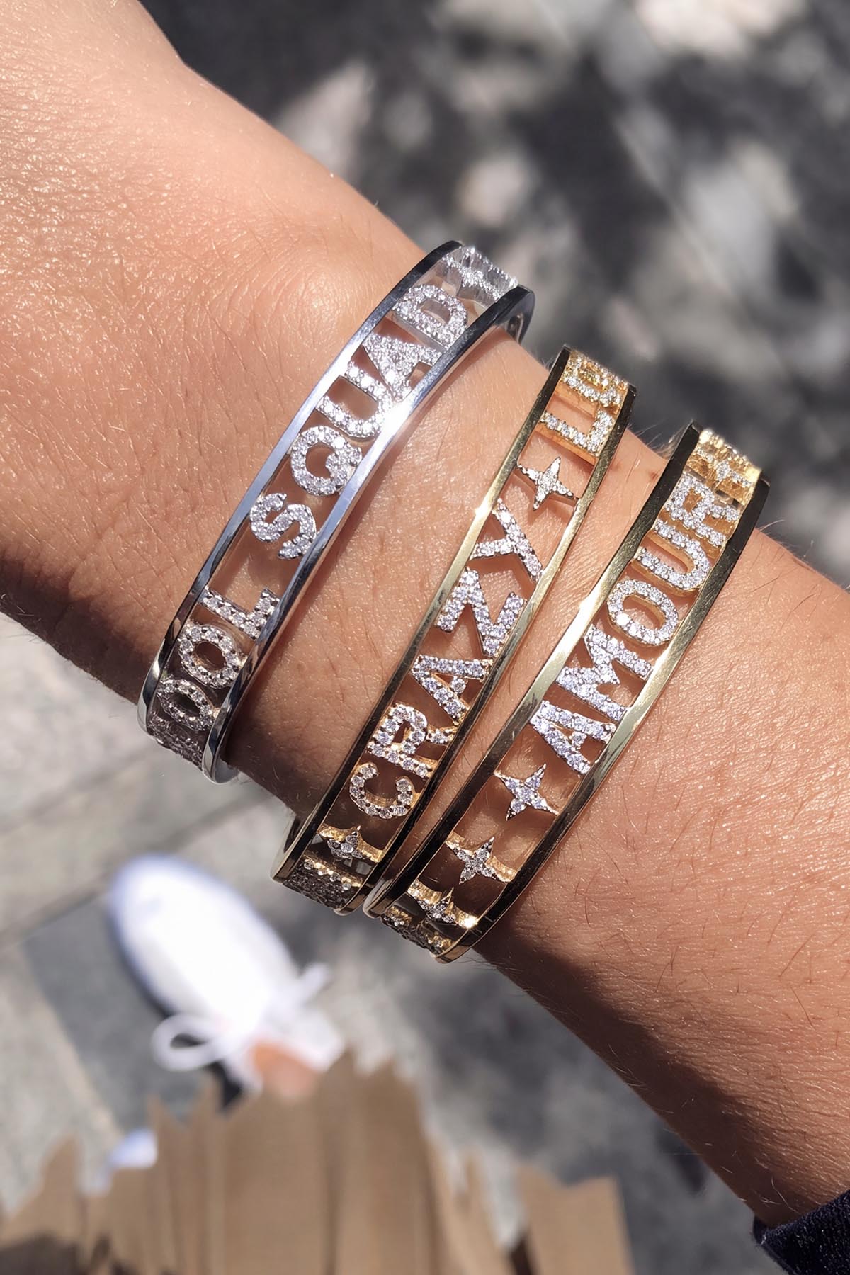 Woman wearing APM Monaco message bangles, a sparkling stack whispering everyday poetry.