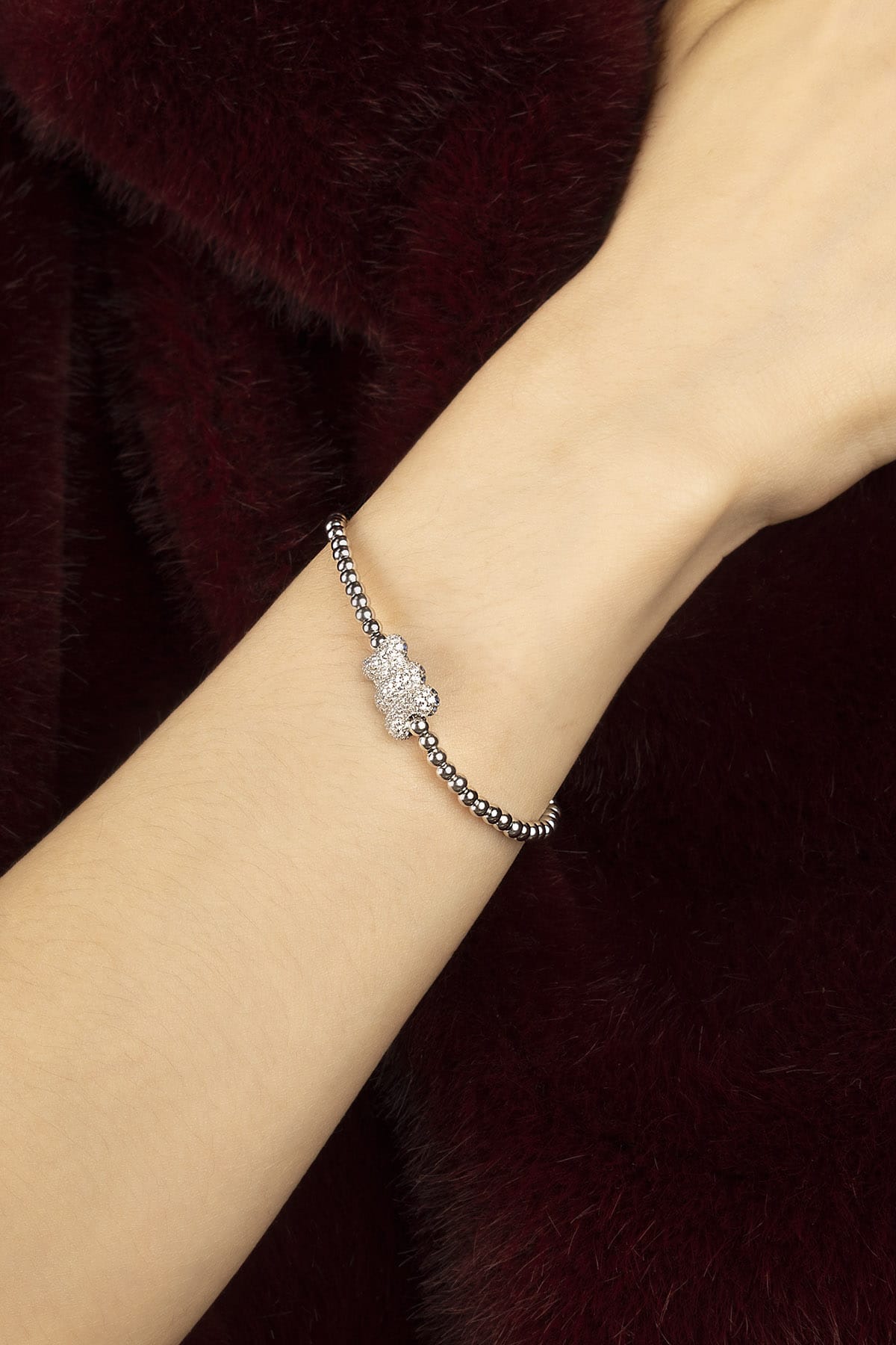 Woman wearing APM beaded bracelet, a playful bear charm shimmering with quiet charm.