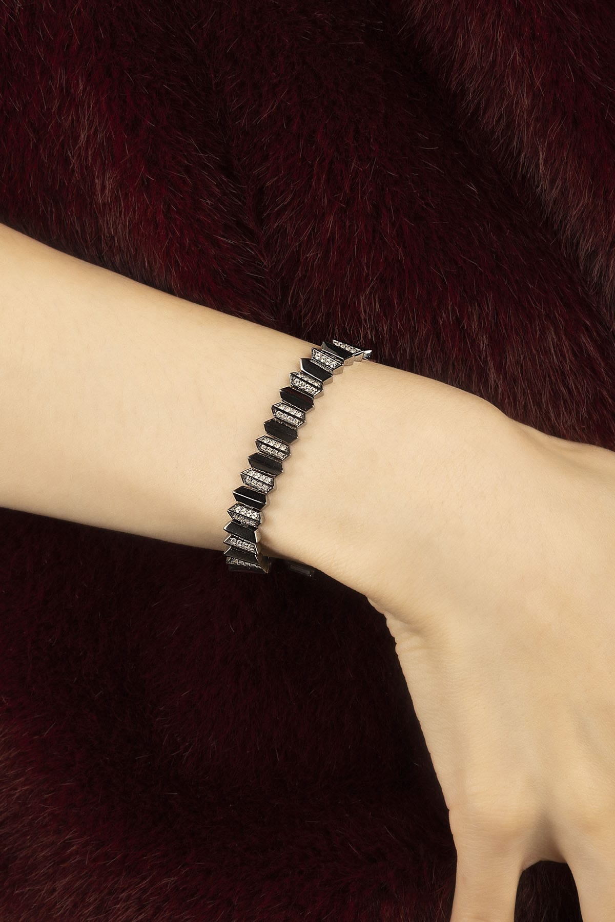 Woman wearing APM Monaco bracelet, bold geometry meets midnight allure.