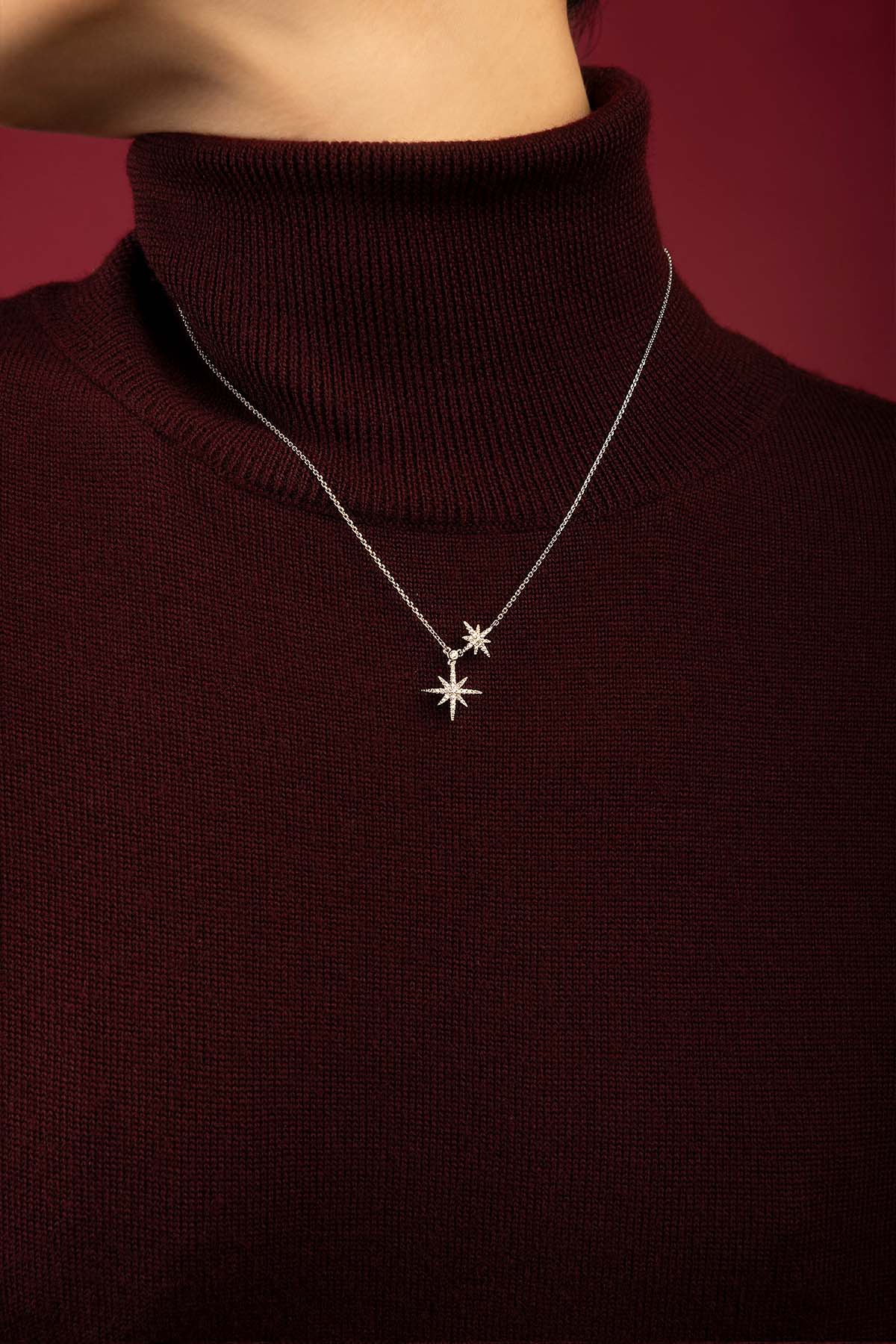 Woman wearing APM Monaco star necklace, a celestial glow on burgundy knit.