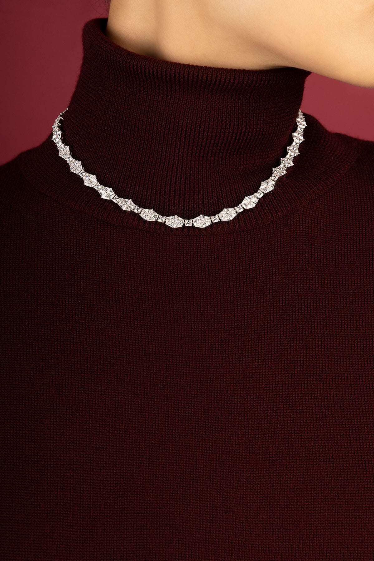 Woman wearing APM necklace, a radiant sparkle over cozy burgundy elegance.