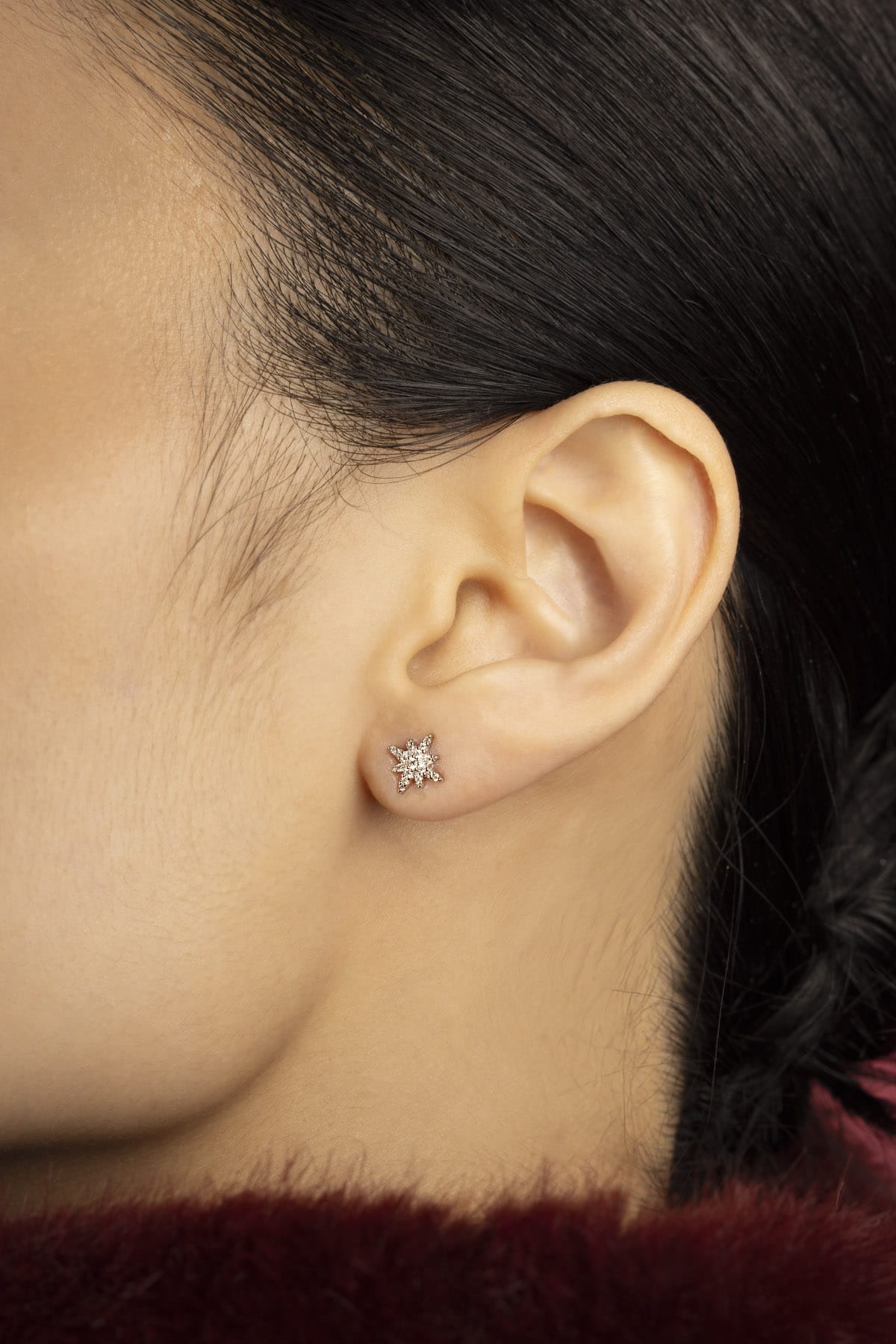 Woman wearing APM star stud earrings, a delicate spark of quiet elegance.