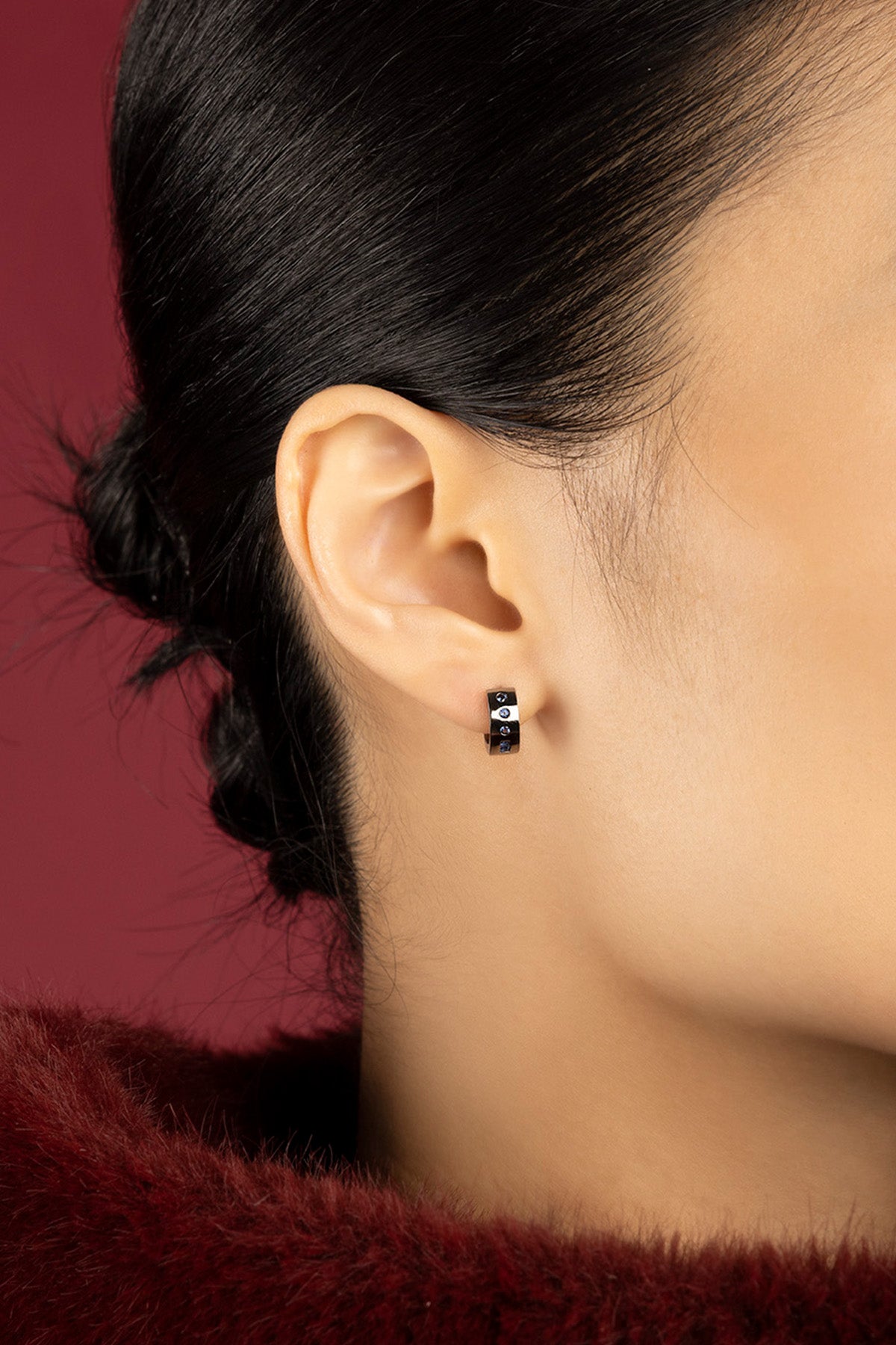 Woman wearing APM Morse Hoop Earrings, a whisper of modern elegance in deep noir.
