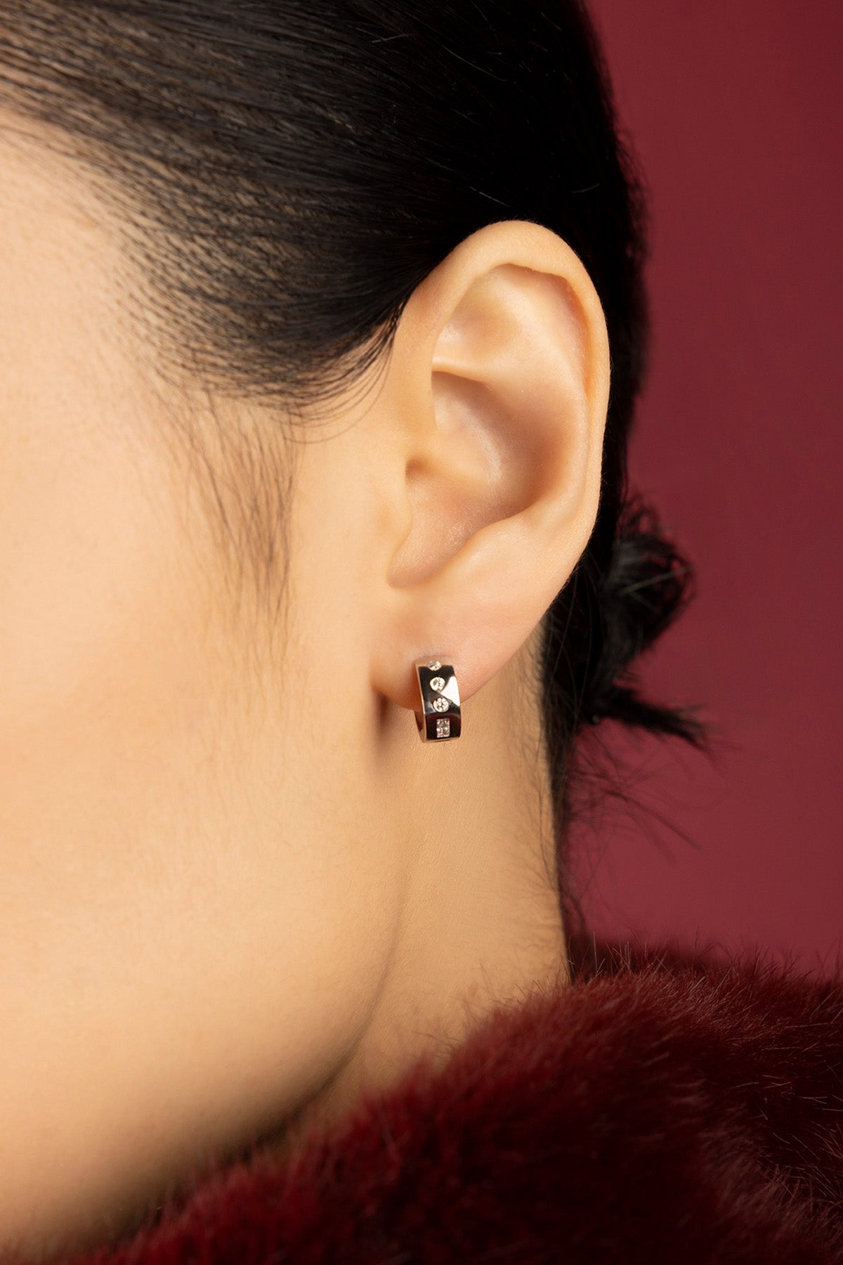 Woman wearing APM Monaco hoop earrings, a whisper of modern elegance in rhodium finish.