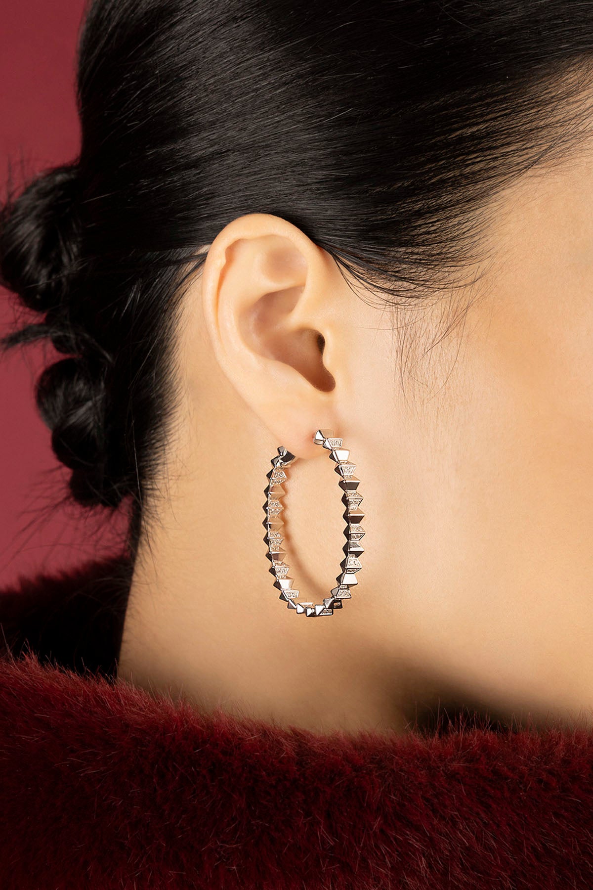 Woman wearing APM hoop earrings, a bold shimmer of edgy elegance.