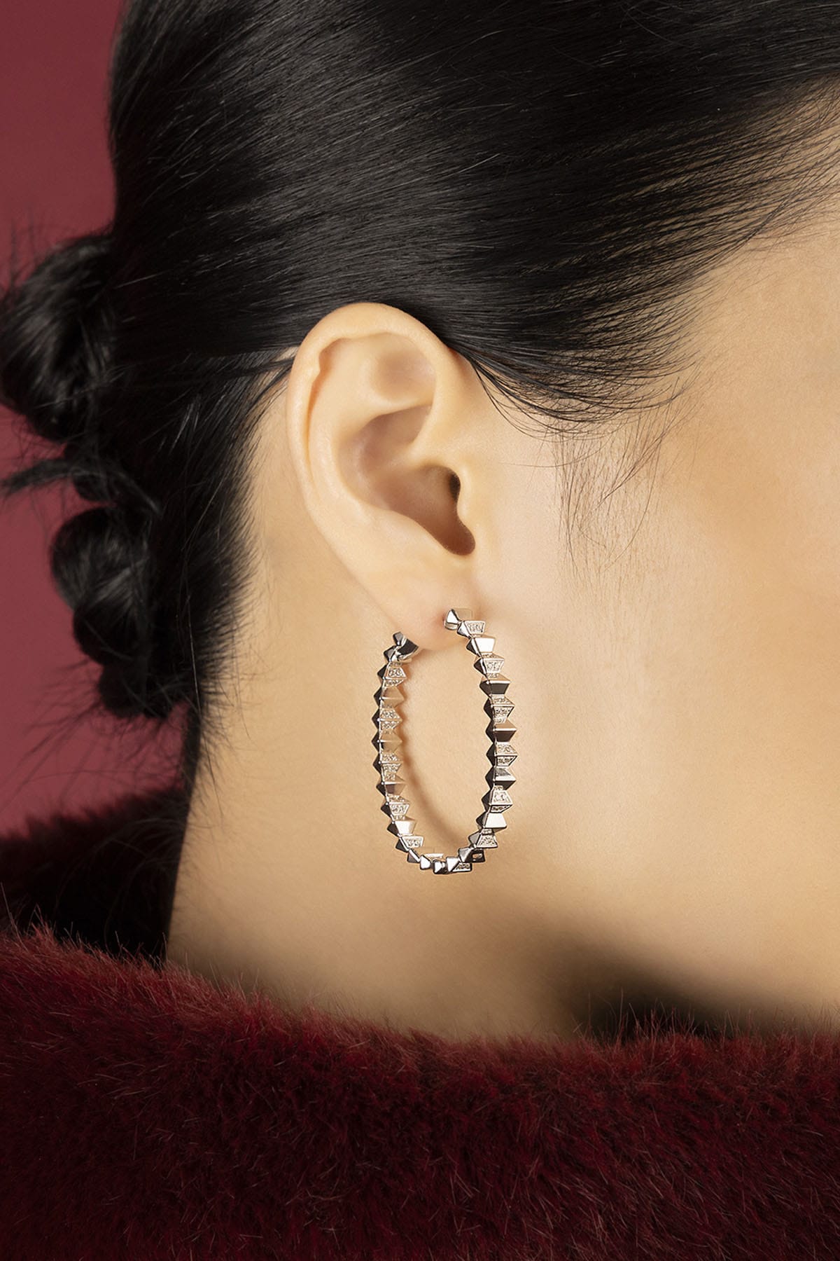 Woman wearing APM hoop earrings, a bold shimmer of edgy elegance.
