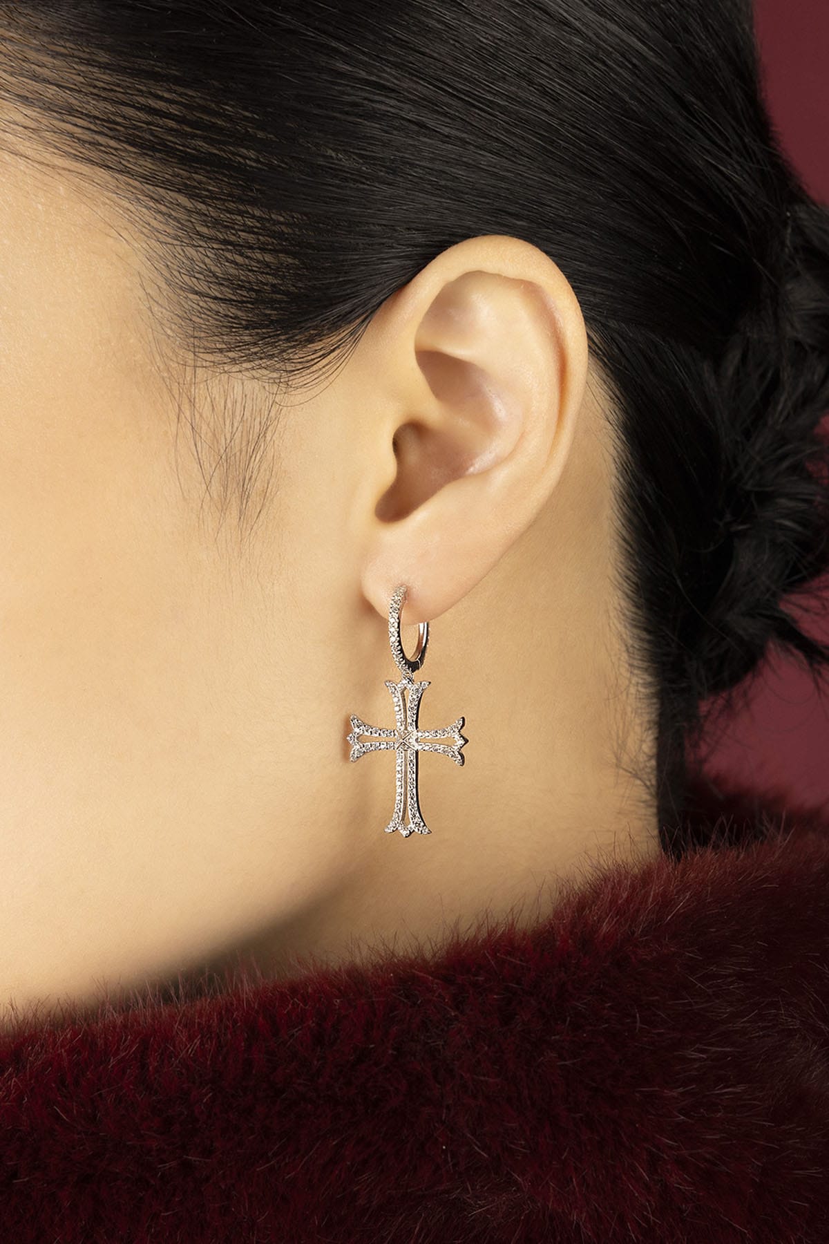 Woman wearing APM cross earrings, a whisper of gothic romance meets modern elegance.