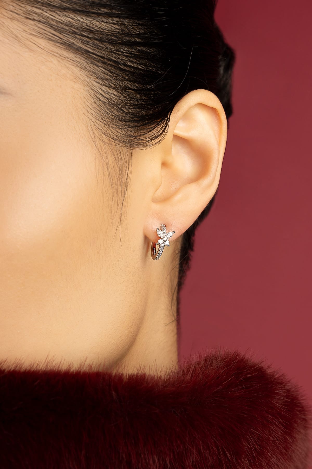 Woman wearing APM butterfly hoop earrings, a delicate whisper of romance.