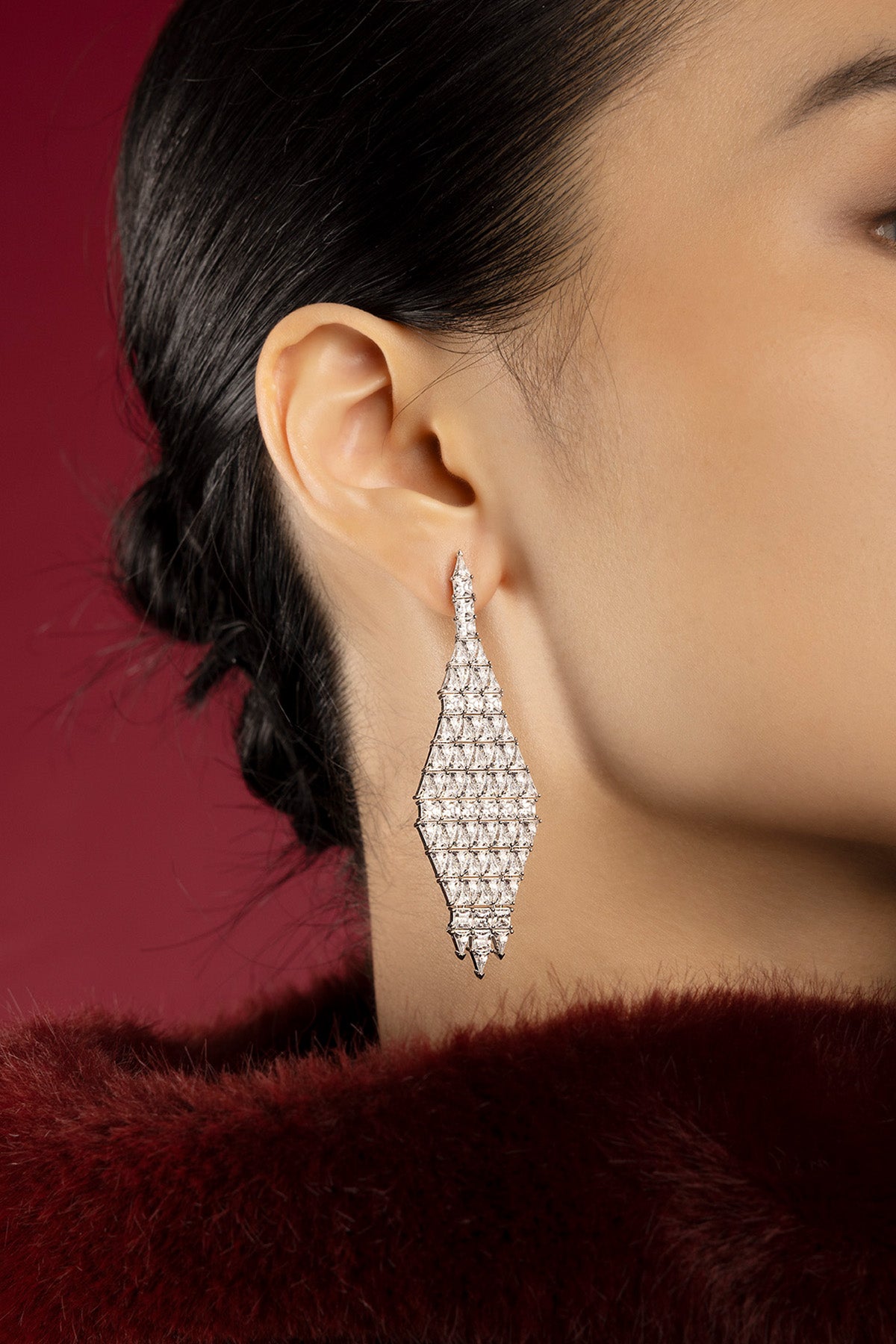 Woman wearing APM Monaco earrings, a shimmering rhombus of quiet evening allure.
