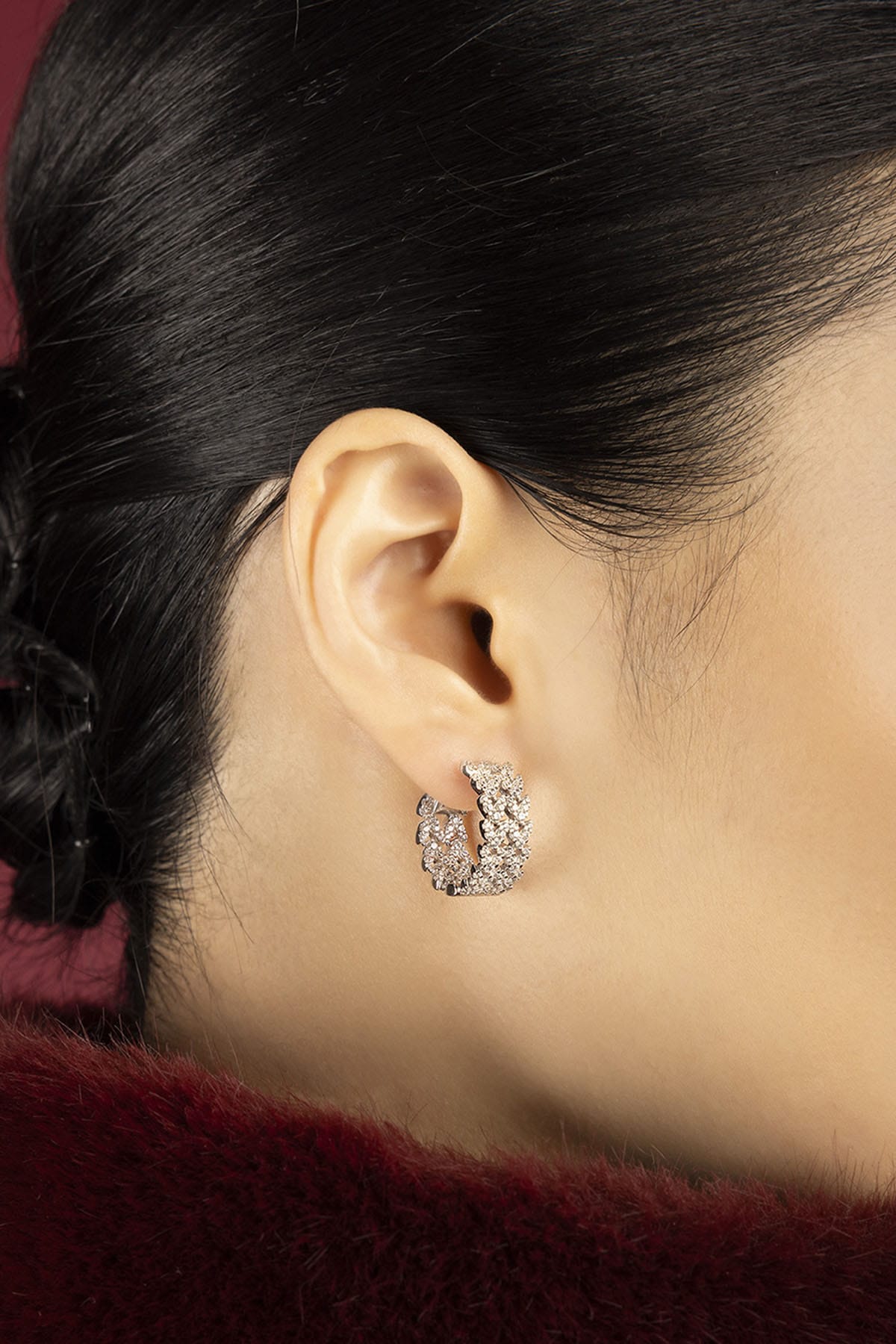 Woman wearing APM hoop earrings, a shimmering whisper of modern elegance.