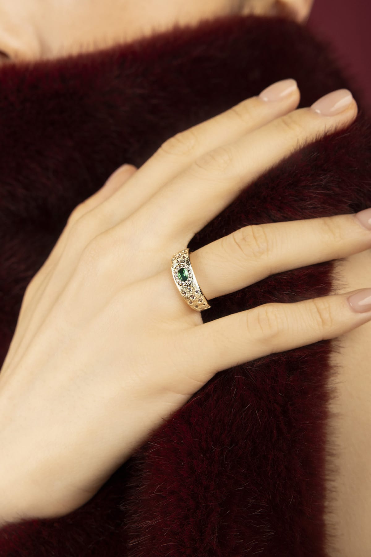 Woman wearing APM ring, a golden whisper of vintage romance and emerald allure.
