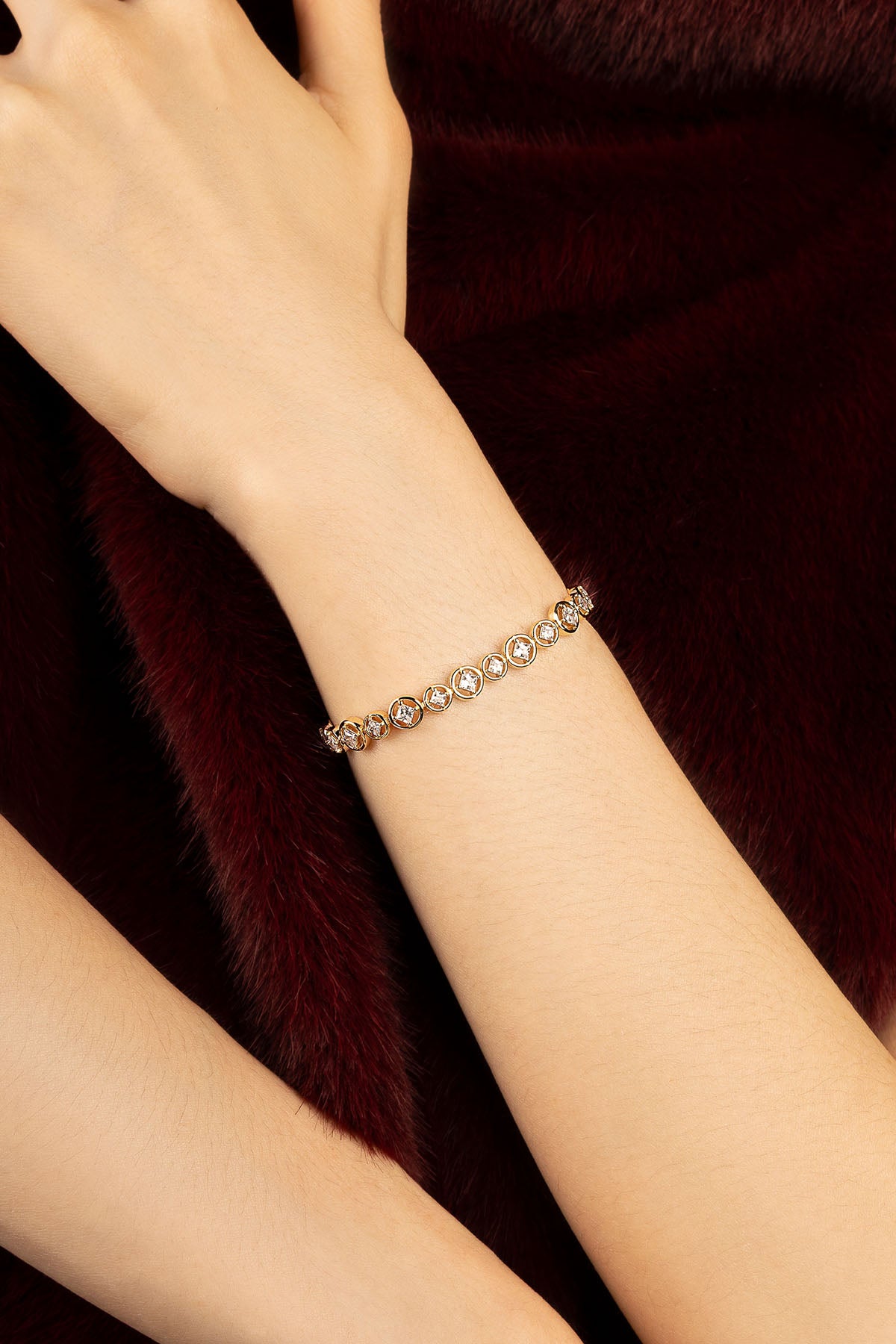 Woman wearing APM bracelet, a delicate glow against deep velvet elegance.