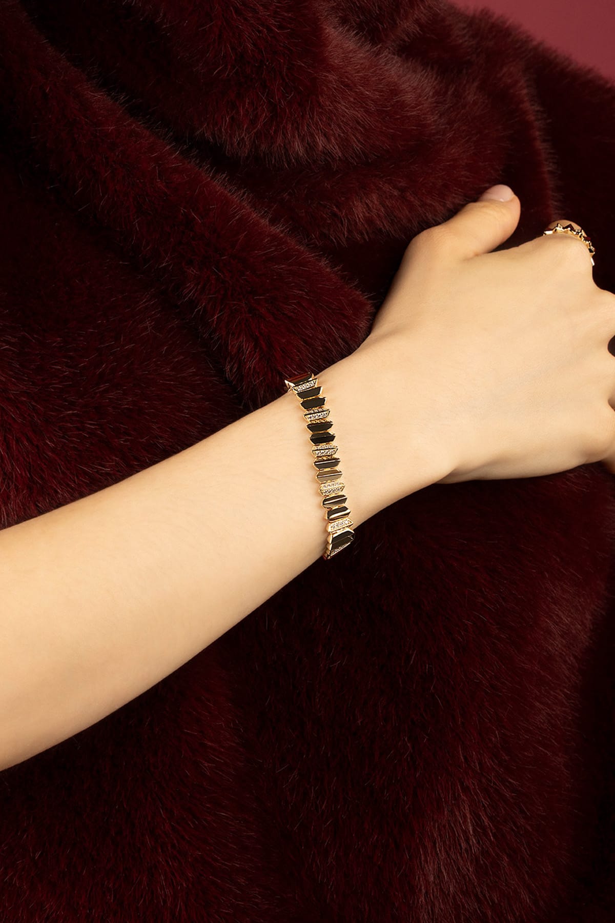 Woman wearing APM bracelet, bold geometry meets velvet allure.