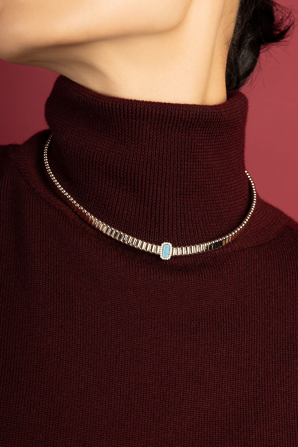Woman wearing APM Monaco necklace, a turquoise whisper against burgundy warmth.