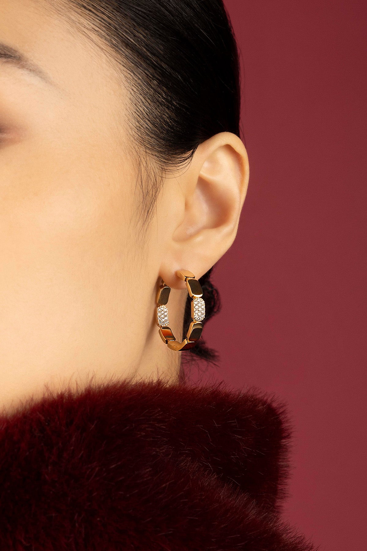 Woman wearing APM hoop earrings, a golden statement glowing with quiet confidence.