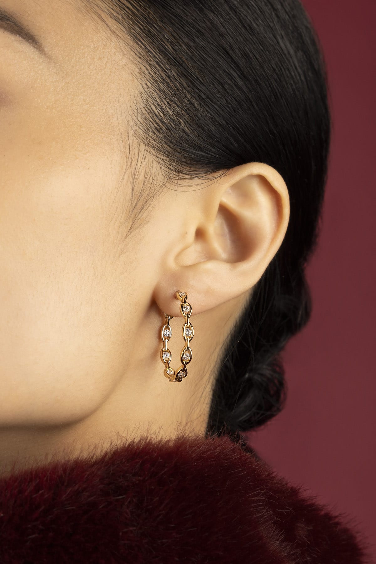 Woman wearing APM Monaco hoop earrings, a golden glow of quiet elegance.
