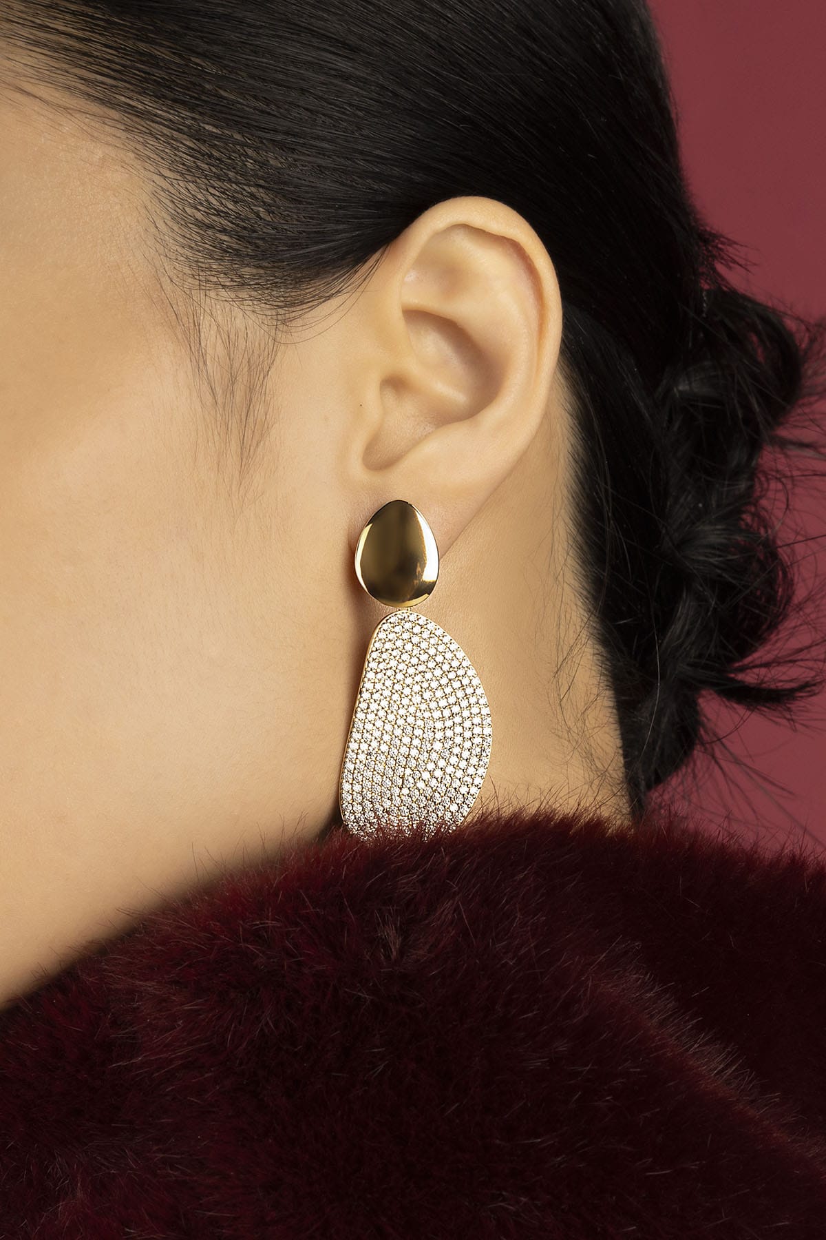 Woman wearing APM Monaco earrings, a golden statement of quiet evening allure.