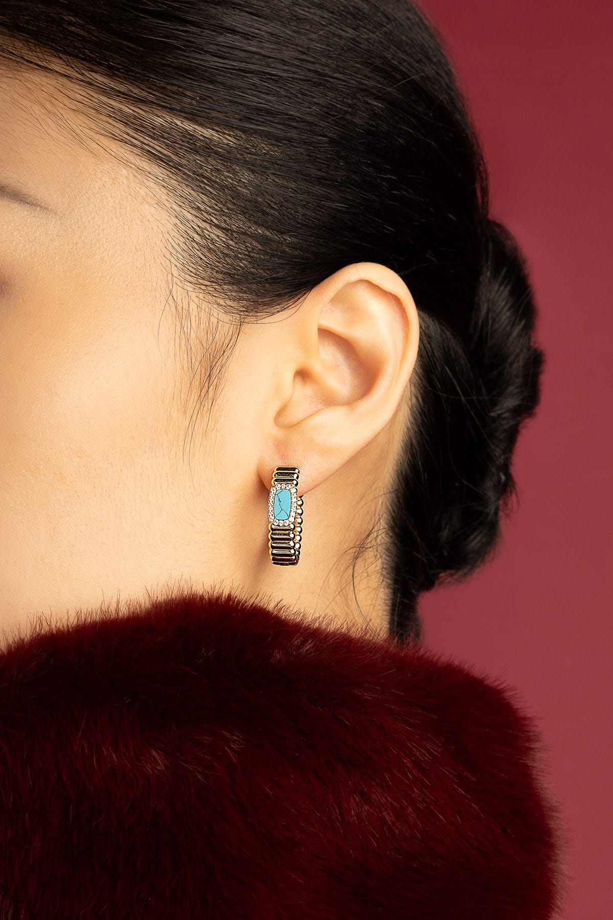 Woman wearing APM Monaco hoop earrings, a turquoise touch of quiet elegance.