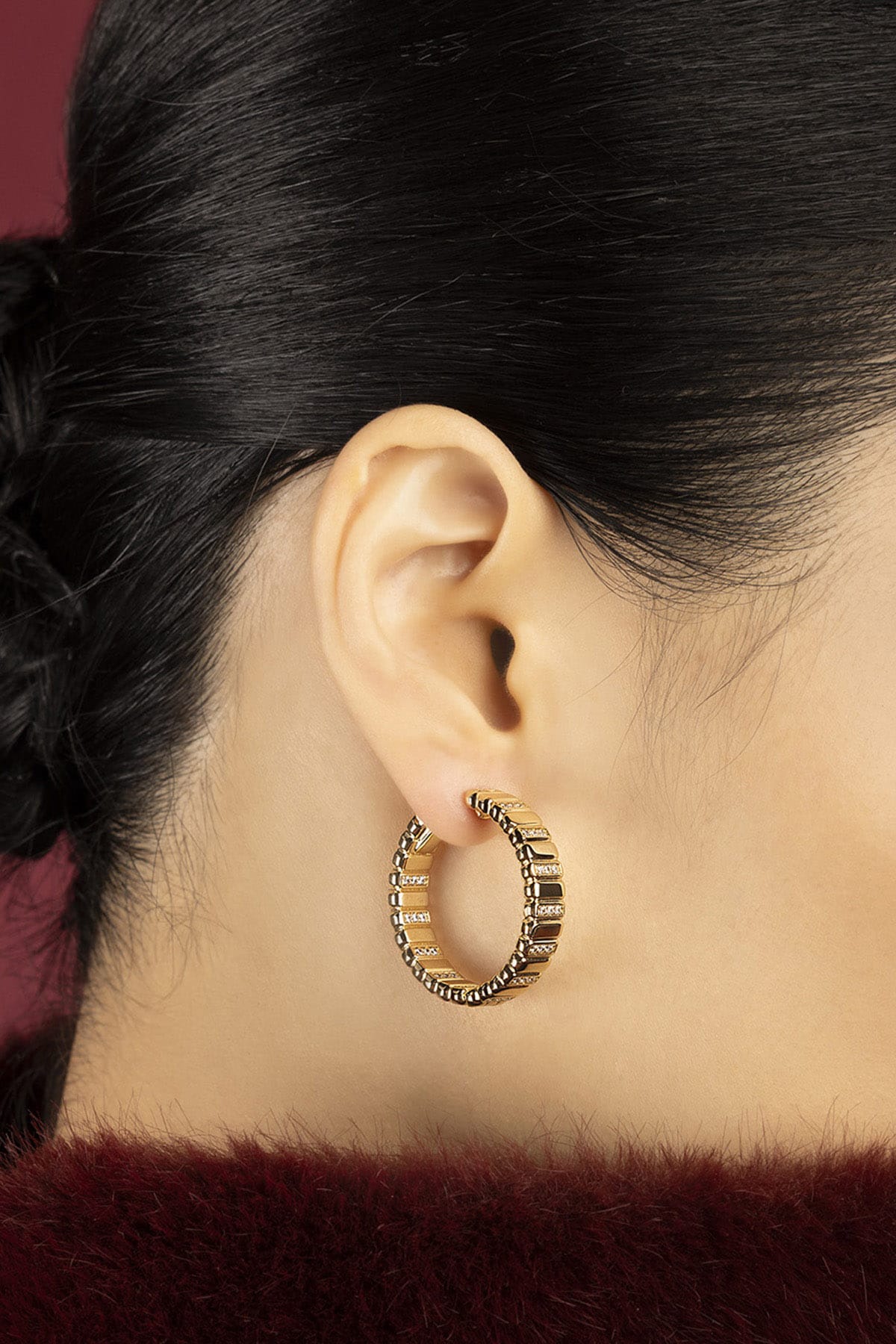 Woman wearing APM Hoop Earrings, a golden statement of quiet confidence.
