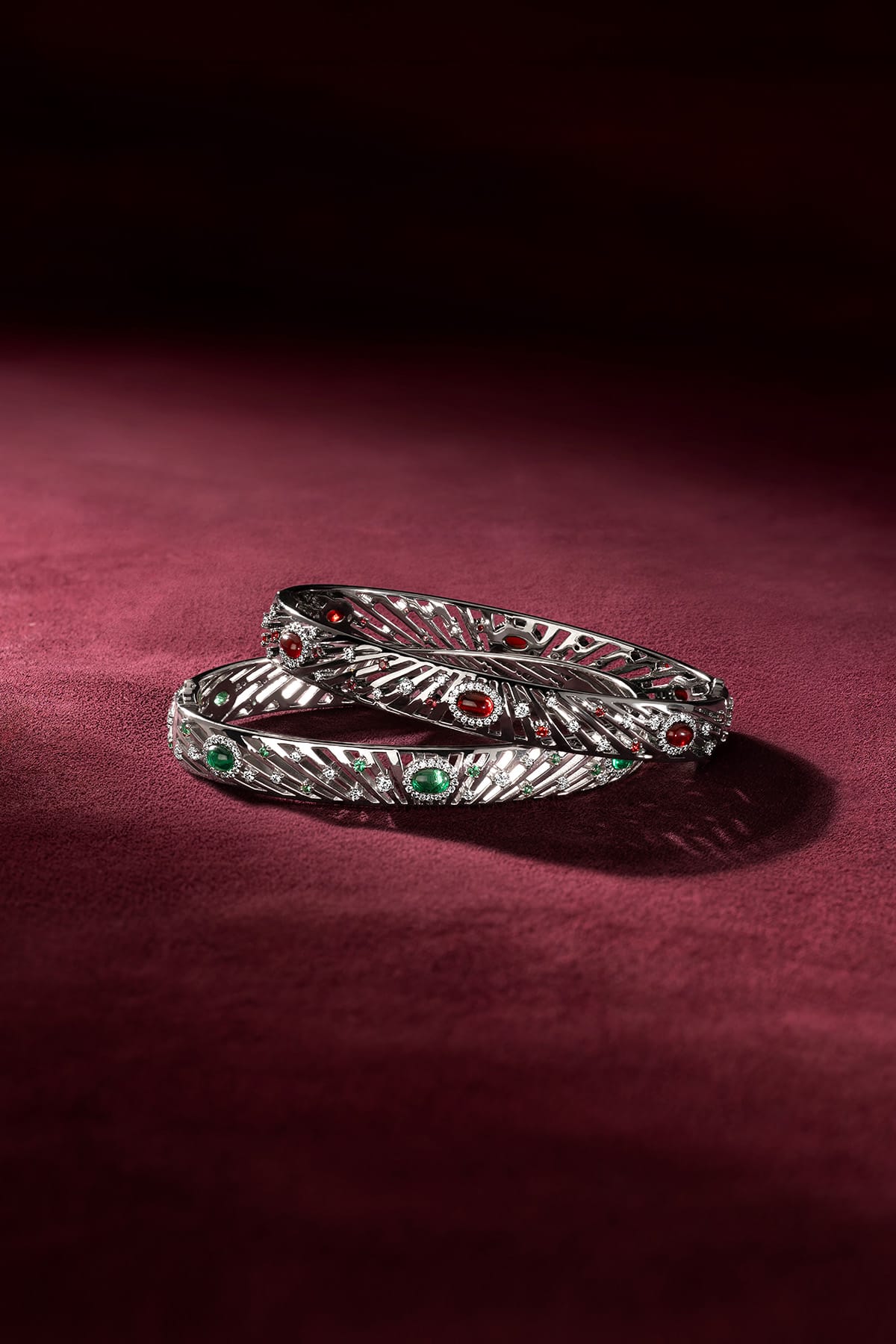 APM Bangles in rhodium finish, glowing with red and green whispers of allure.