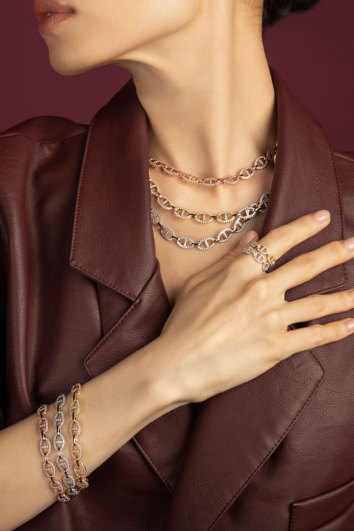 Woman wearing APM Morse chain necklaces, bracelets and ring, layered in bold elegance.