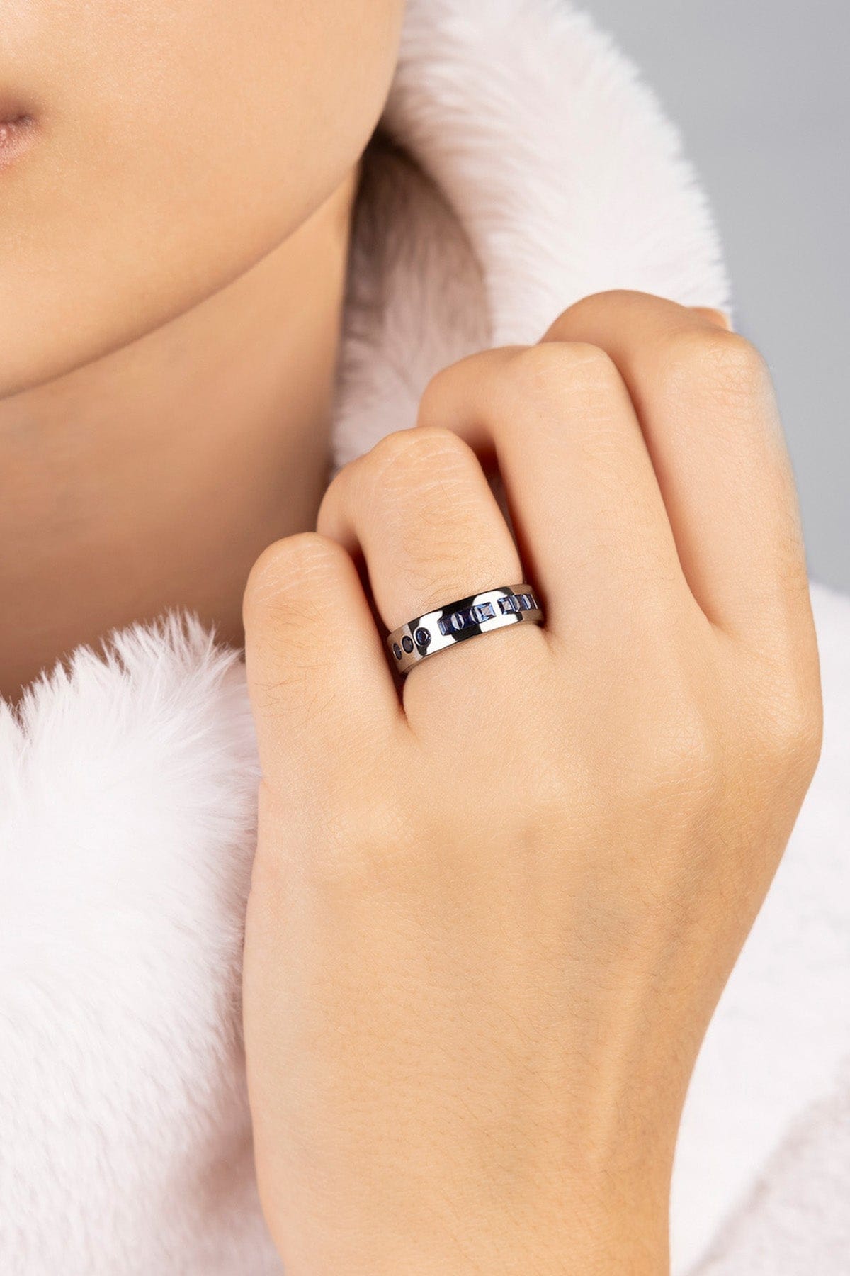 Hand wearing a silver ring with a white fur background