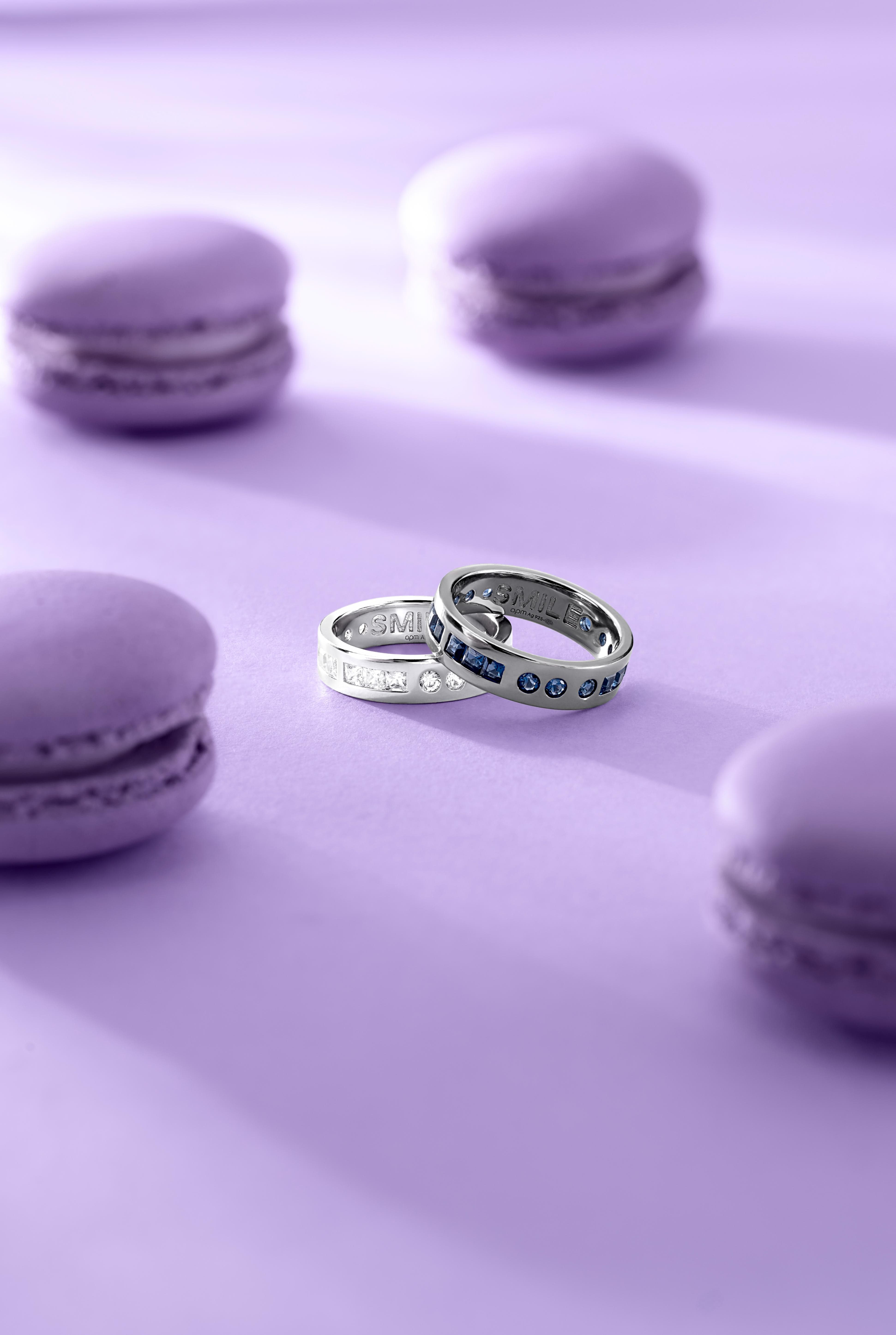 Two rings on a purple surface with macarons in the background