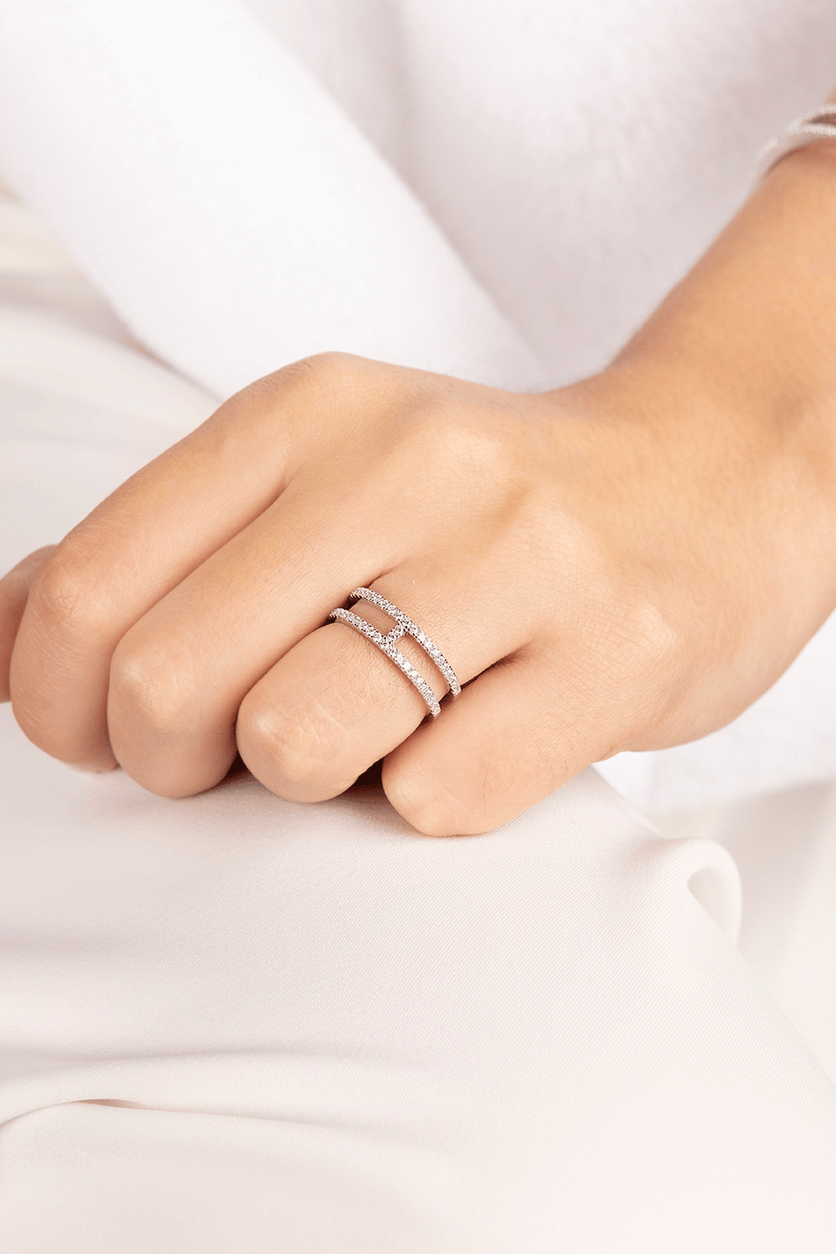 Close-up of a hand wearing APM MONACO silver ring with double-line design on a white background