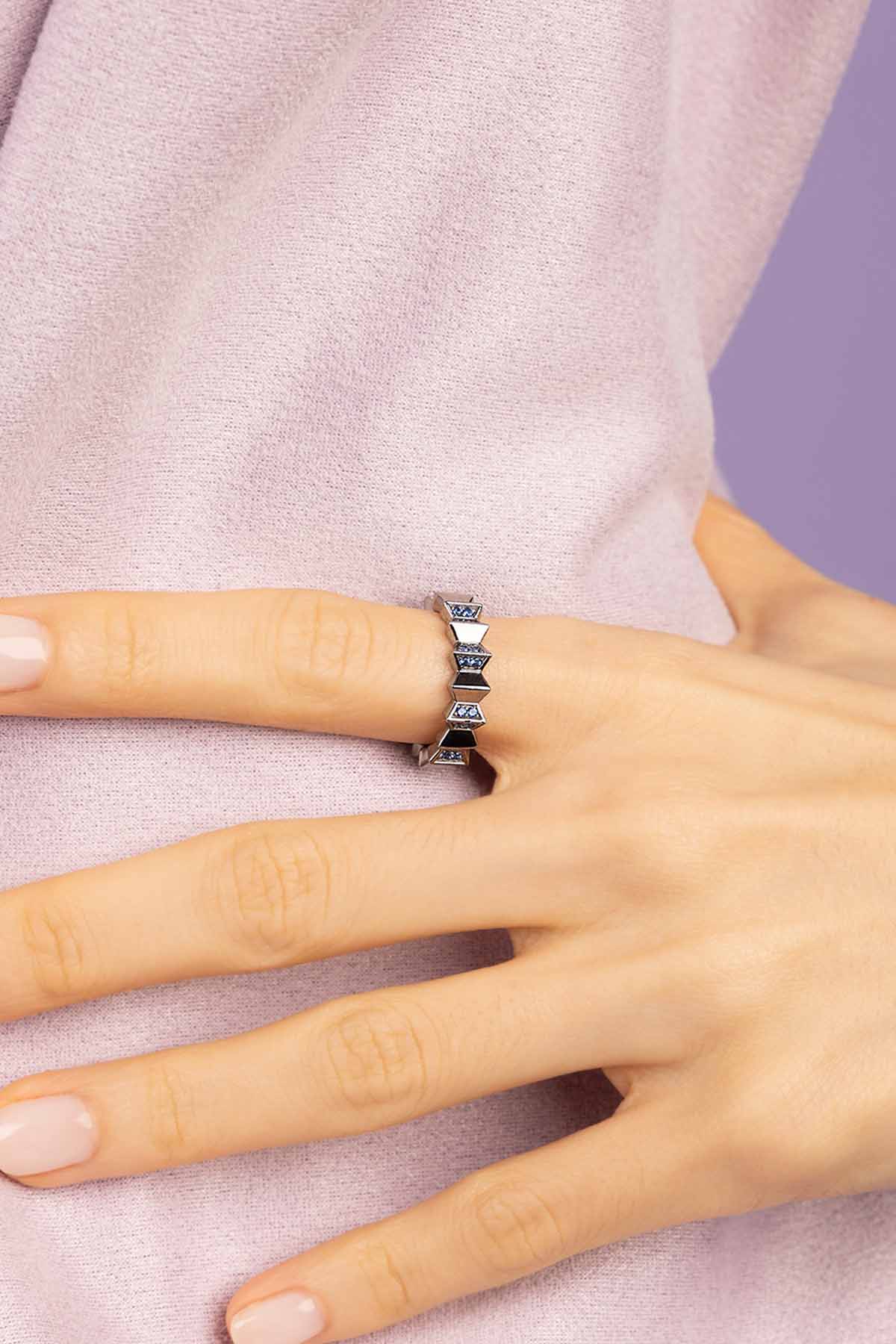 Hand wearing a Silver-tone ring on a light pink background