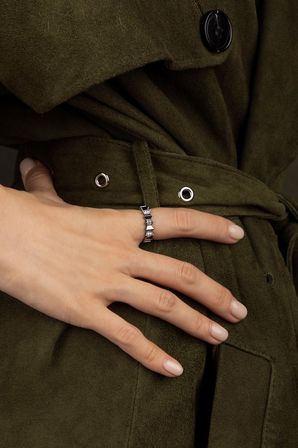 Close-up of a hand wearing a ring on a green coat background