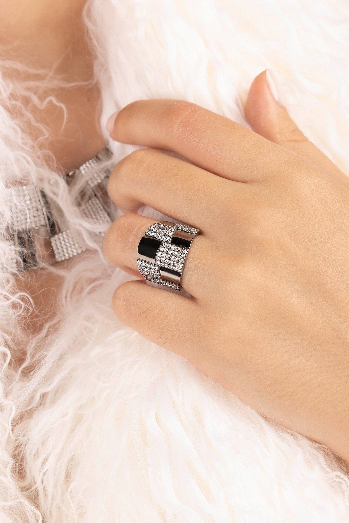 Close-up of a hand wearing a silver ring with a black center on a white background
