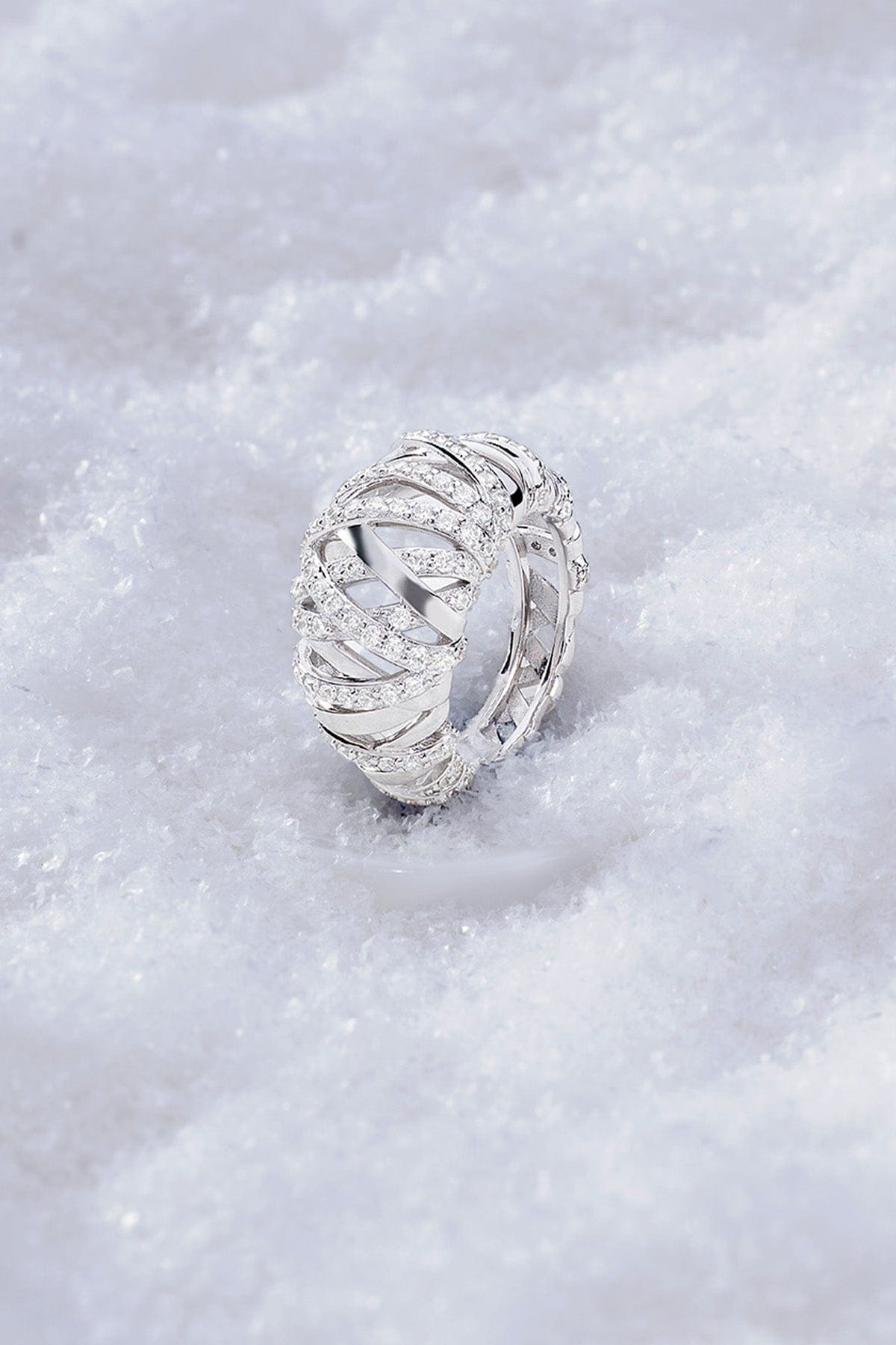 APM MONACO enlace ring in silver with intricate design on a snowy background