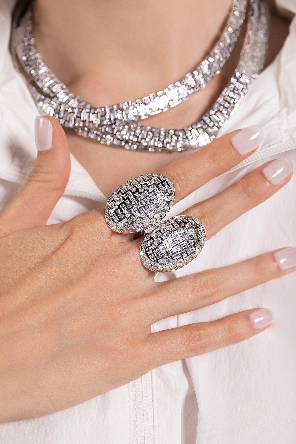 Close-up of a hand wearing two silver APM MONACO labyrinth rings with a white background