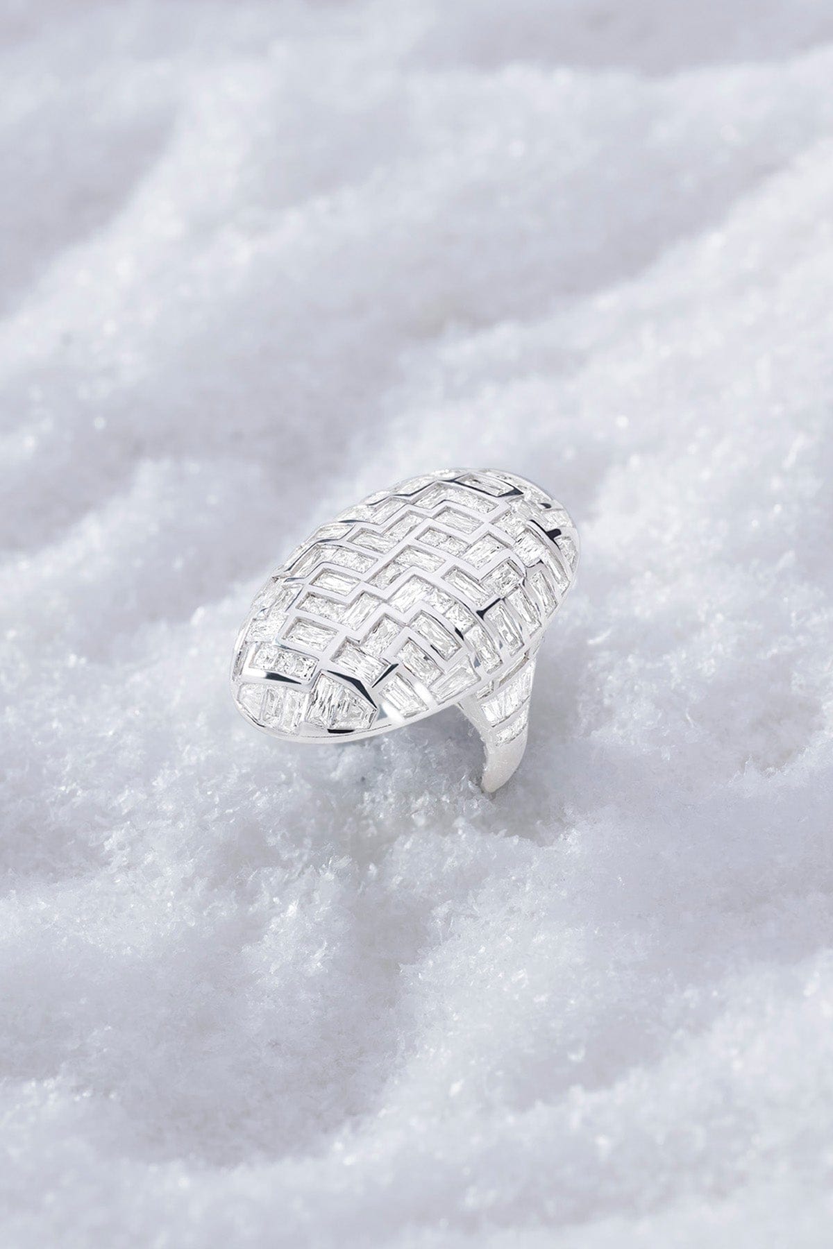 APM MONACO statement labyrinth ring in silver with a textured design on a white snowy background