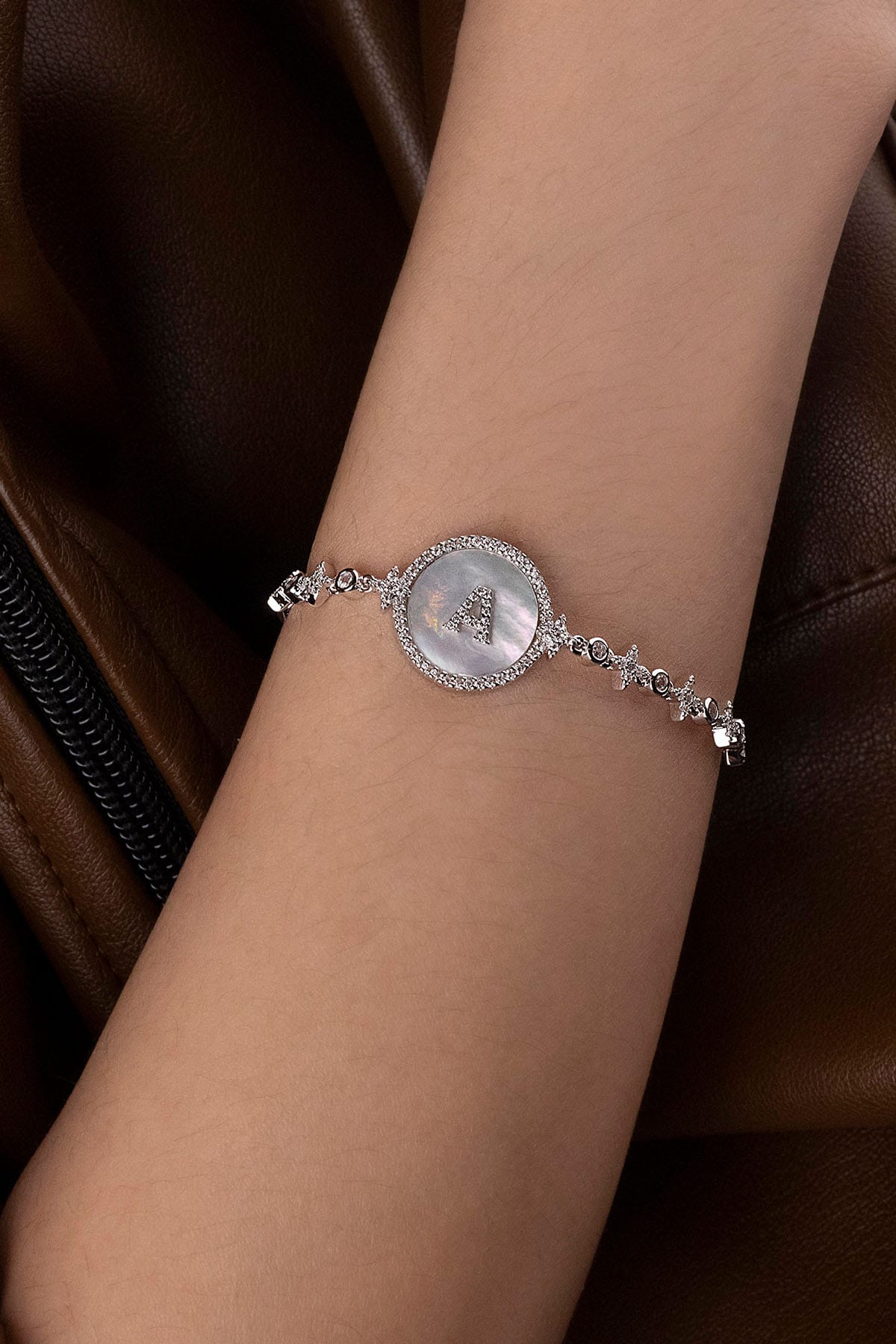 Bracelets APM Monaco adjustable bracelet in silver with a round mother-of-pearl charm bearing the letter A, surrounded by pavé diamonds.
