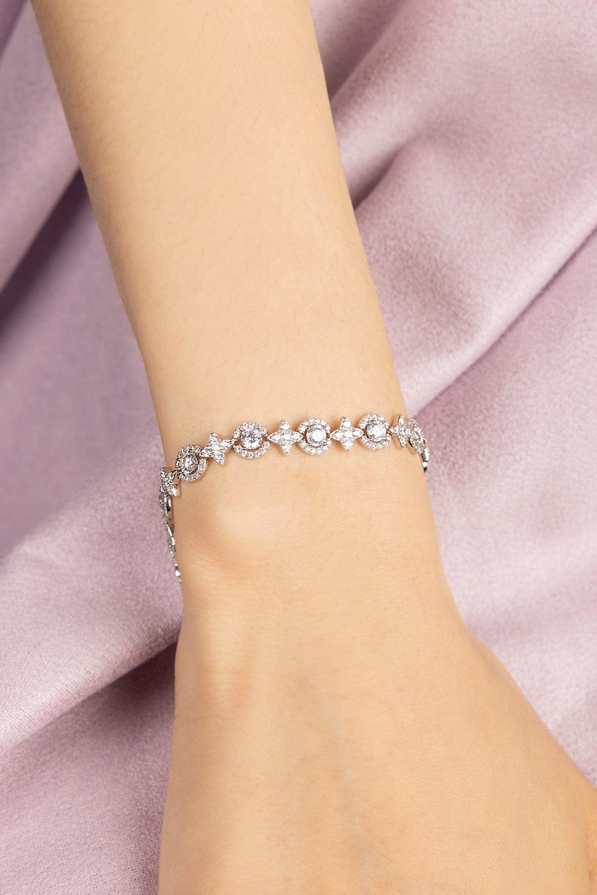 Silver bracelet on a person's wrist against a pink fabric background
