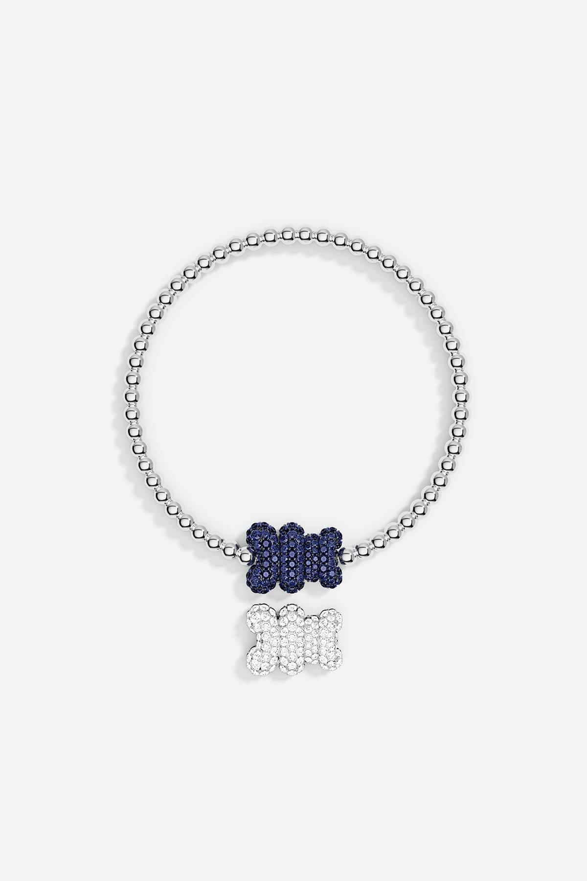 Bracelets APM Monaco: stretch beaded bracelet in silver-tone beads with two bone-shaped pendants, a blue pendant on the chain and a white pendant that dangles.