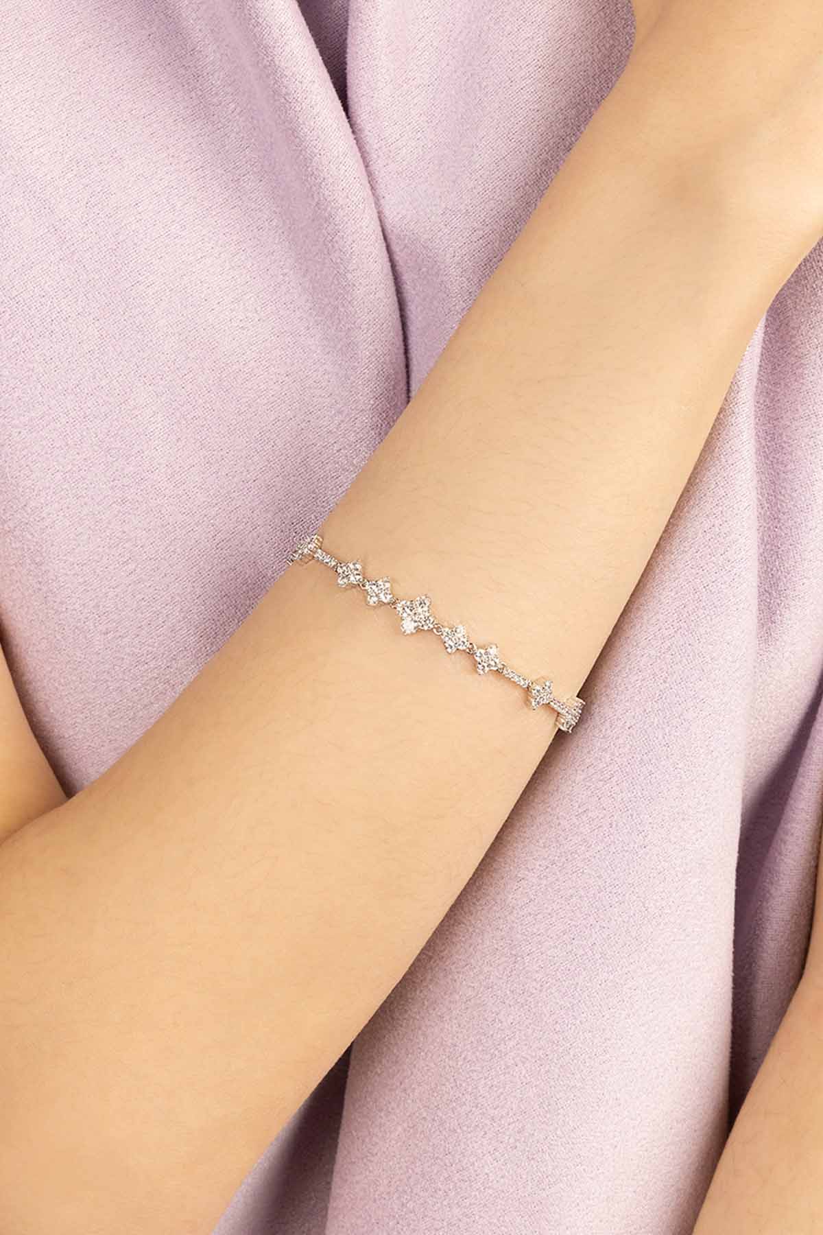 Silver bracelet with zirconia on a wrist against a soft pink fabric background
